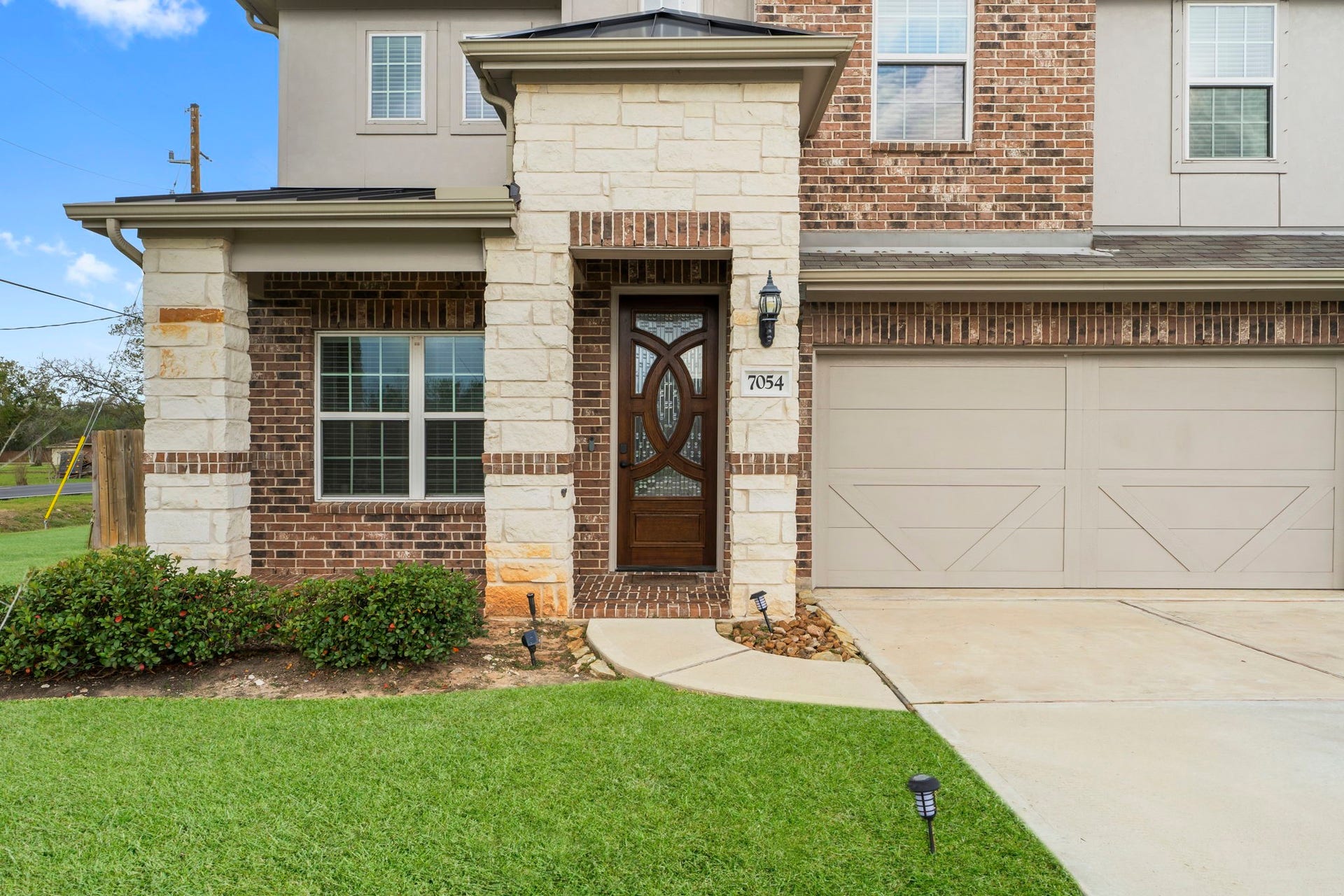7054 Terra Drive, Manvel, TX 77578 Elegant front entry with stone columns, detailed wood door, and modern fixtures.