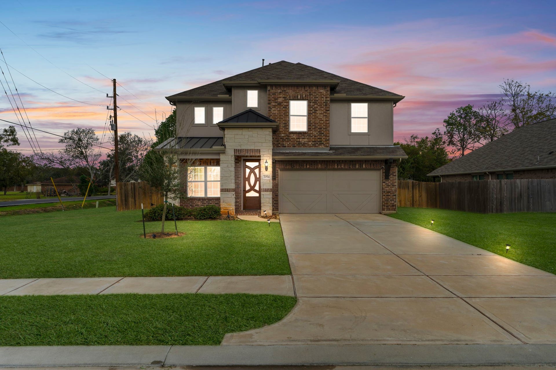 7054 Terra Drive, Manvel, TX 77578 Stunning twilight elevation showcasing the home's elegant brick and stone faade.