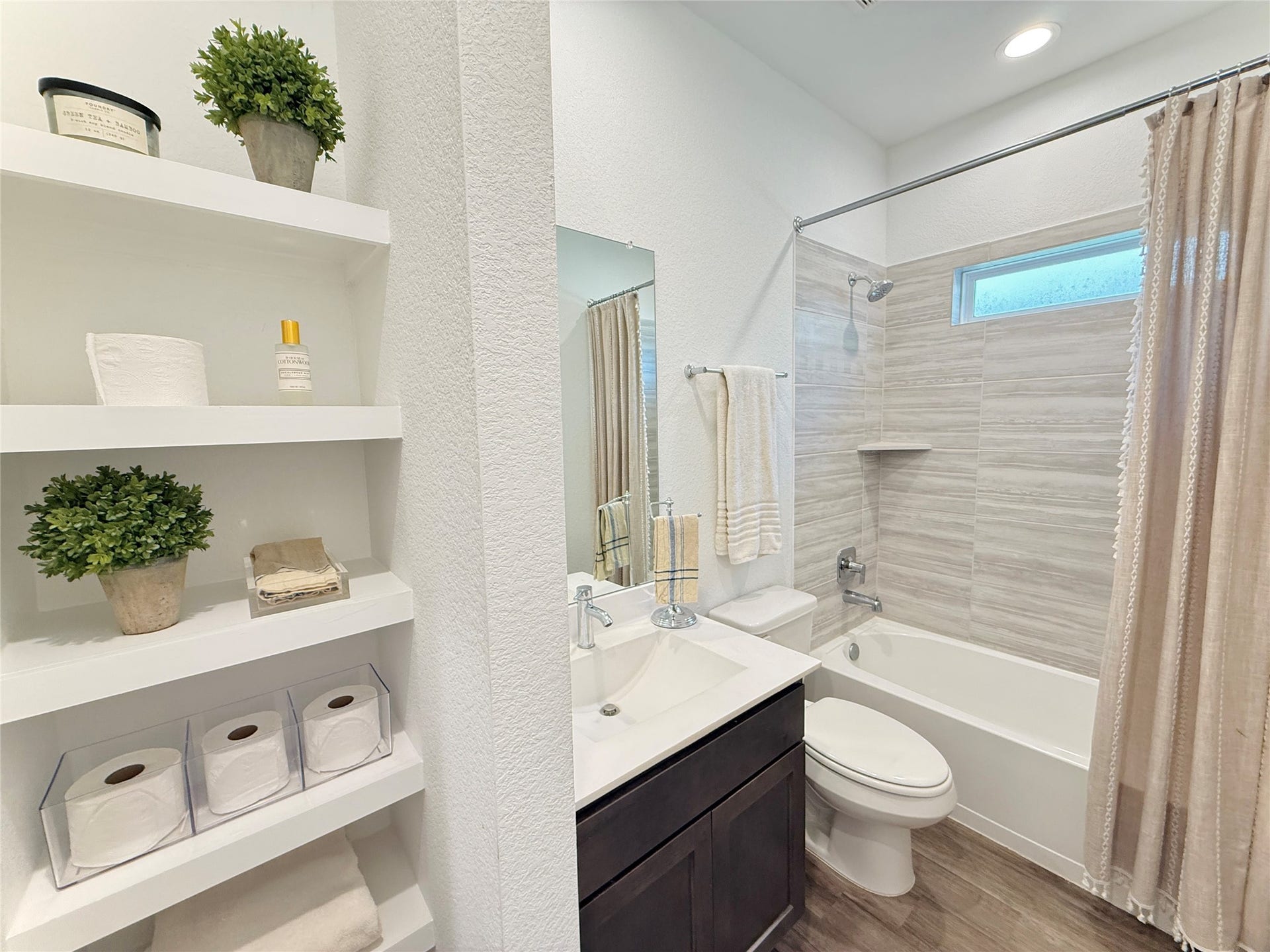 Bright and modern bathroom featuring a sleek vanity, tiled shower, and convenient built-in shelving for storage.