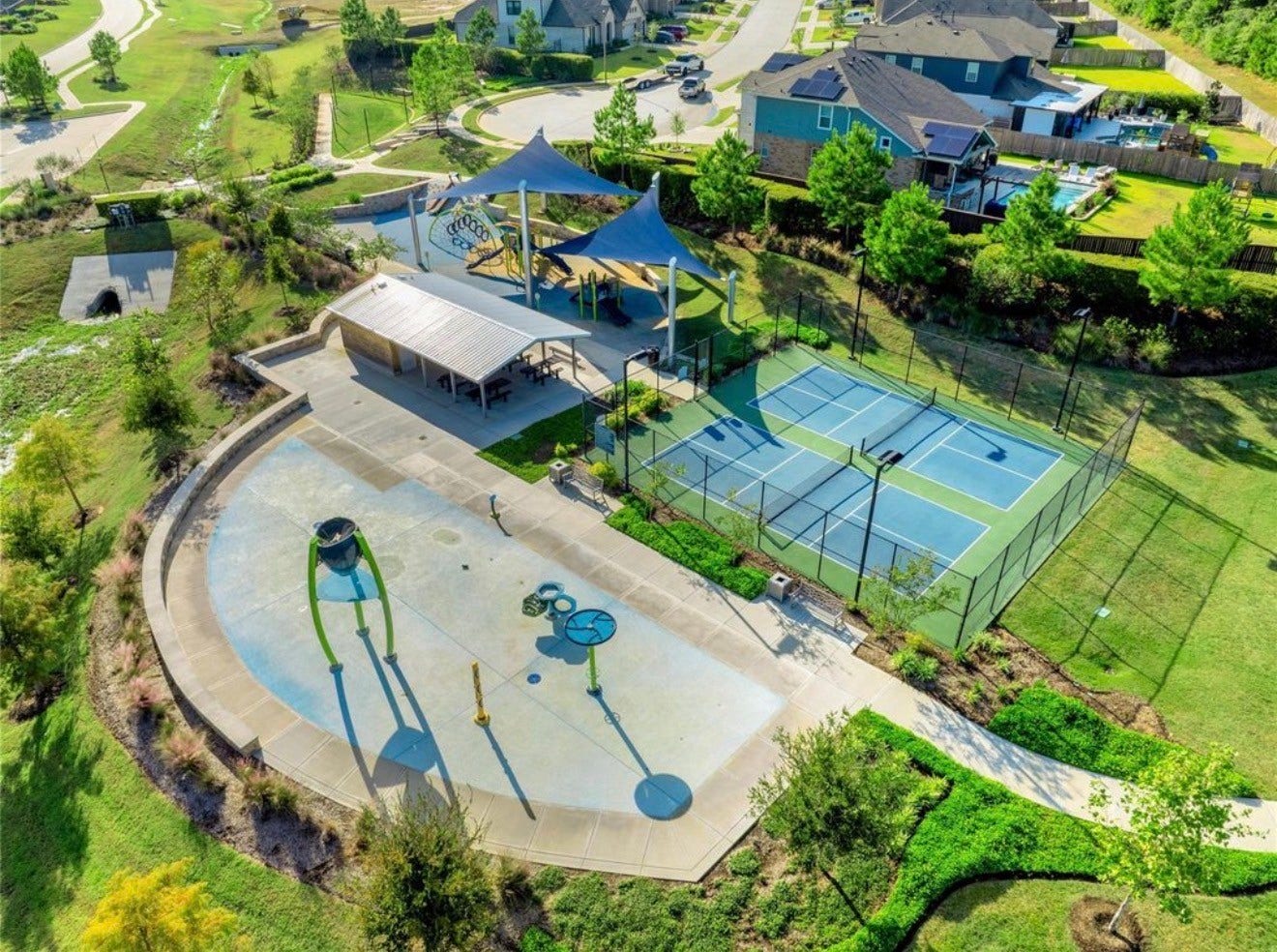 Neighborhood park featuring a splash pad, shaded playground, picnic tables, tennis courts and walking paths.