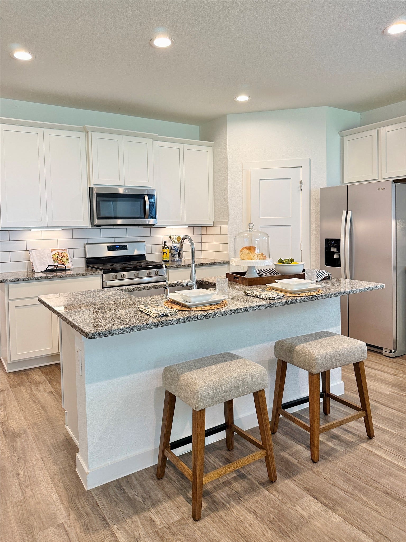 Bright and modern kitchen featuring sleek granite countertops, stainless steel appliances, and a spacious island with seating, perfect for entertaining
