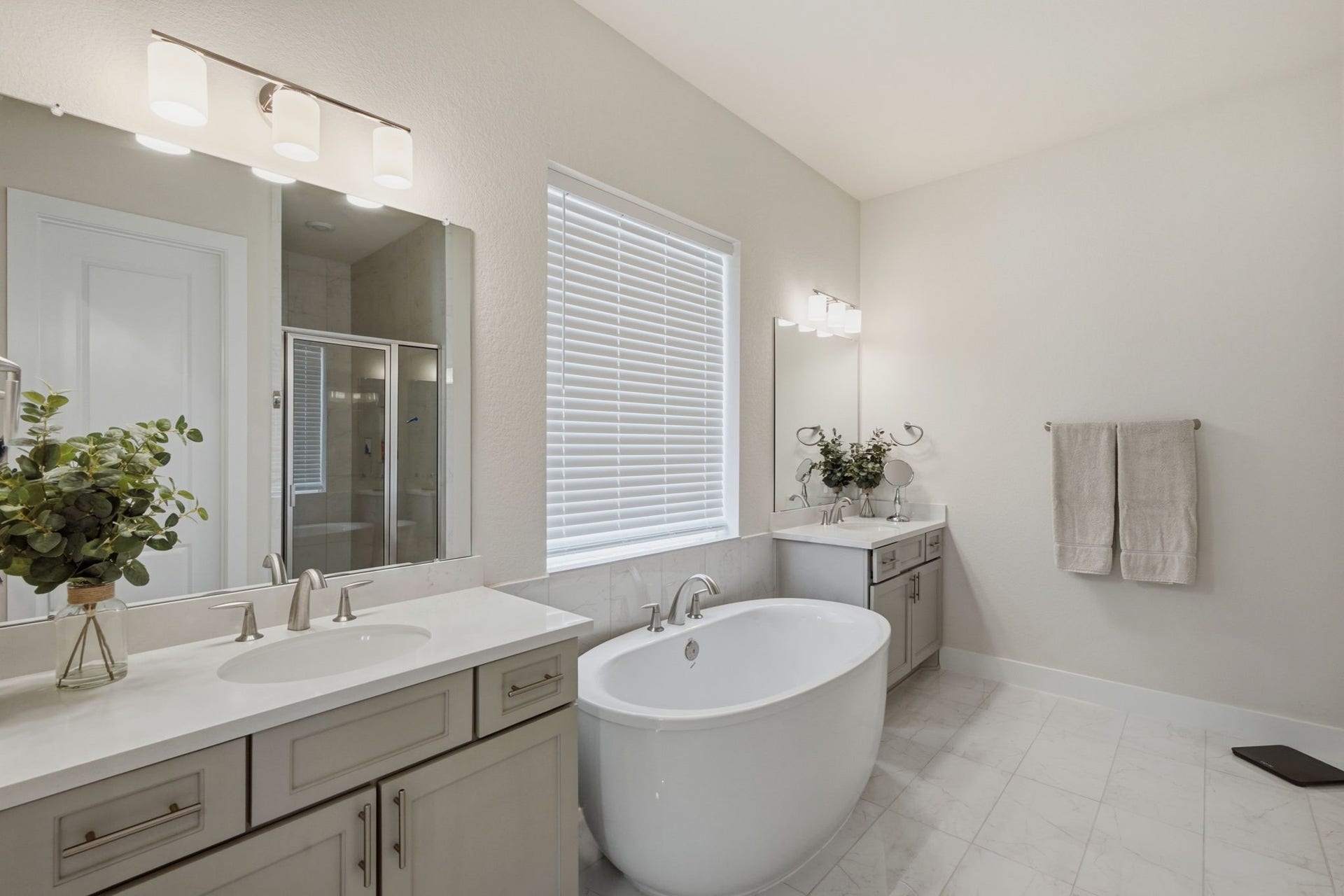 24615 Lukes Landing Way, Tomball, TX 77375 Elegant Primary bathroom featuring a freestanding tub, double vanity with modern fixtures, and a spacious glass-enclosed shower, all accented by soft lighting and neutral tones.
