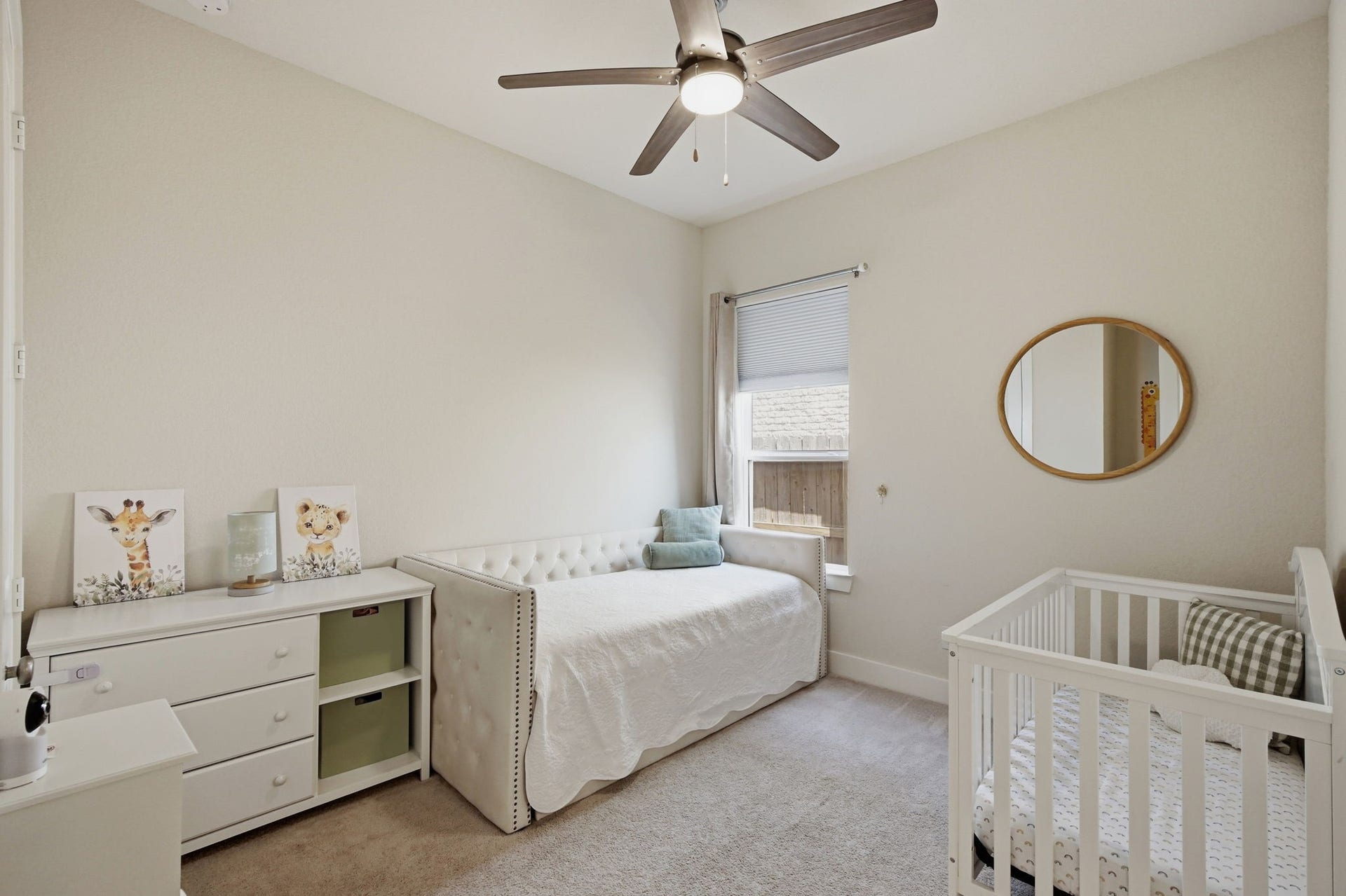 24615 Lukes Landing Way, Tomball, TX 77375 Charming nursery featuring soft neutral tones, a cozy crib, and a daybed, complemented by a ceiling fan and natural light from a window.