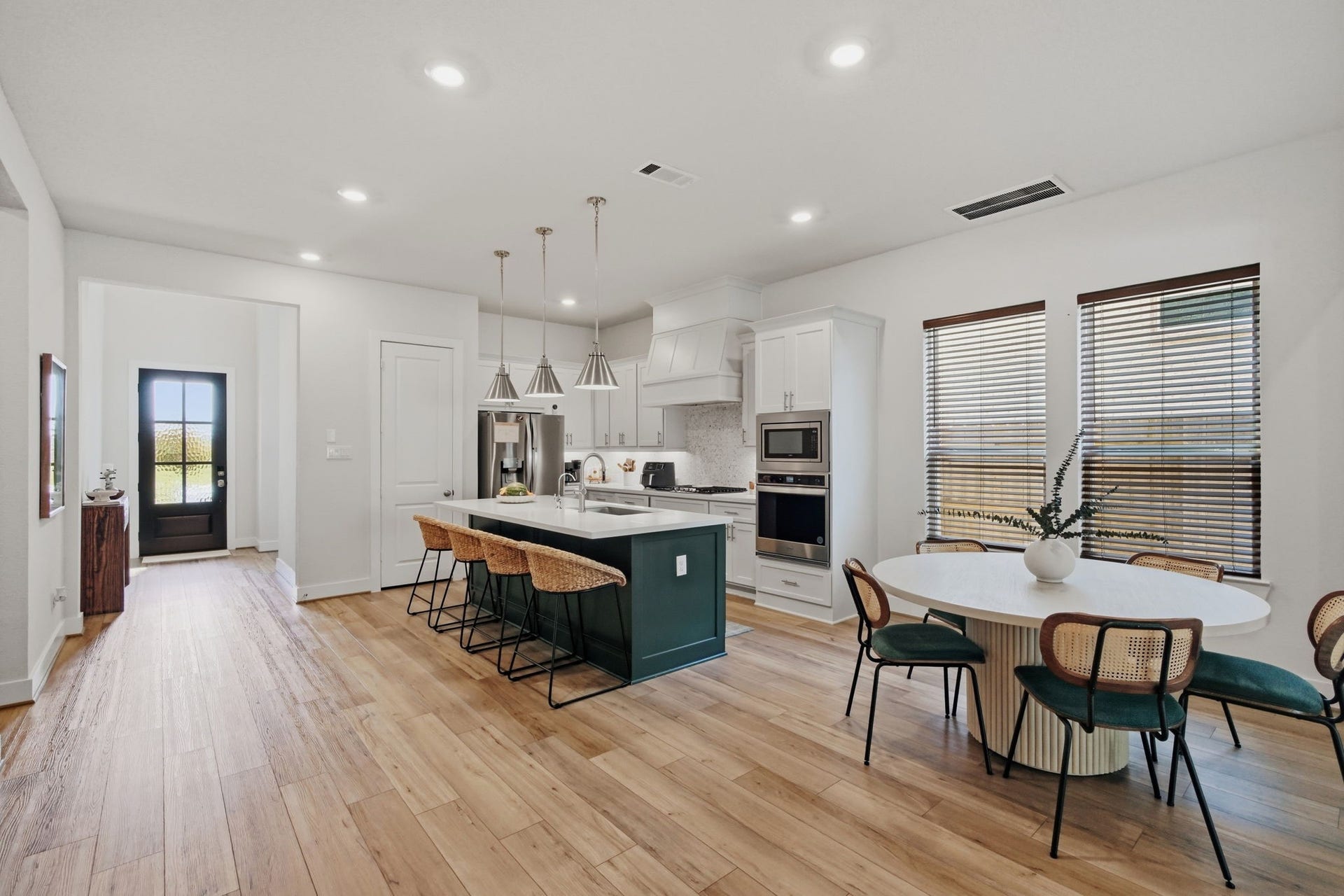 24615 Lukes Landing Way, Tomball, TX 77375 Bright and spacious kitchen with a large island, modern appliances, and an inviting dining area, all enhanced by natural light and elegant wood flooring.