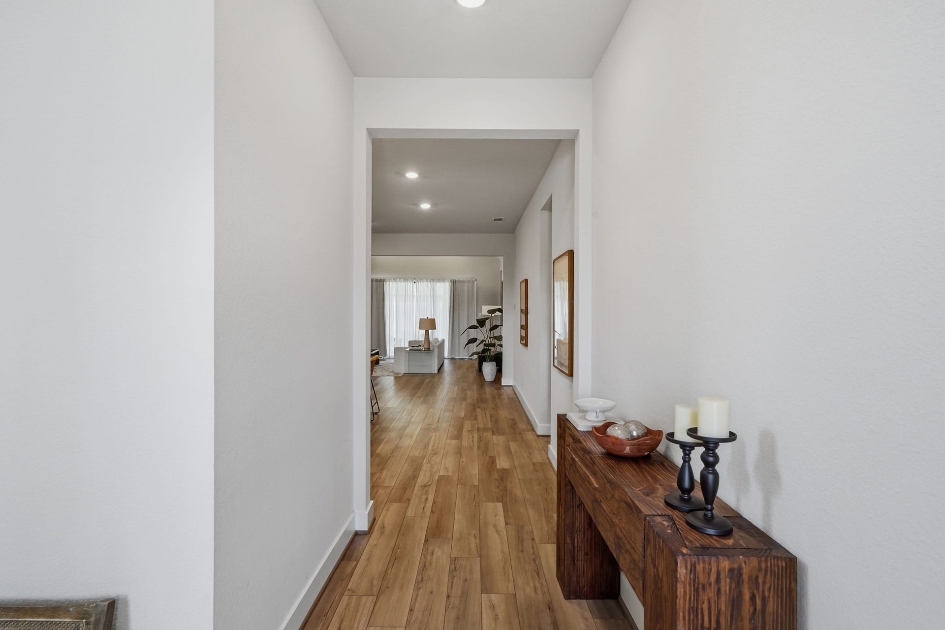 24615 Lukes Landing Way, Tomball, TX 77375 Inviting hallway with warm wood flooring leads to a bright, open living space, enhanced by elegant decor and soft lighting.