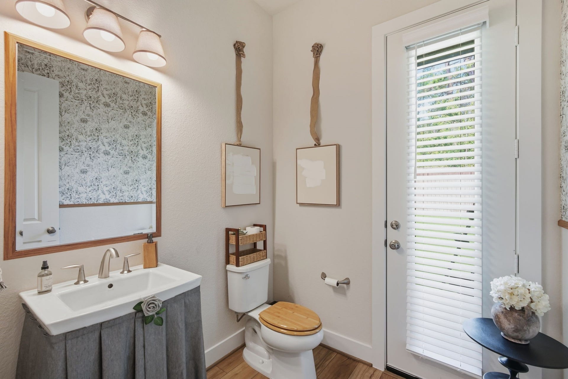 24615 Lukes Landing Way, Tomball, TX 77375 Charming 1/2 bathroom with elegant fixtures, a decorative mirror, and natural light streaming through a glass door with blinds.