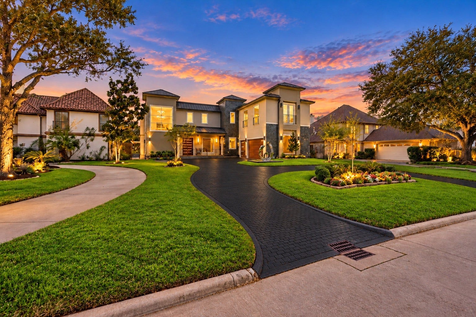 Beautifully illuminated exterior framed by mature landscaping and a sweeping circular driveway. A polished-steel sculpture by an Argentine artist serves as a striking focal point, establishing the home's connection between architecture, art, and landscape.