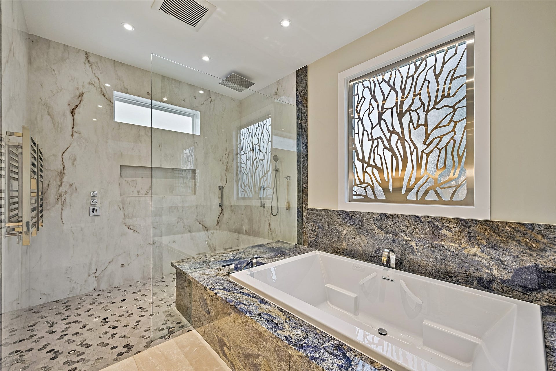 Luxurious bathing area featuring a soaking tub, elegant stone surrounds, and a separate glass-enclosed shower. Sophisticated finishes and a spacious layout create a private, spa-like retreat.