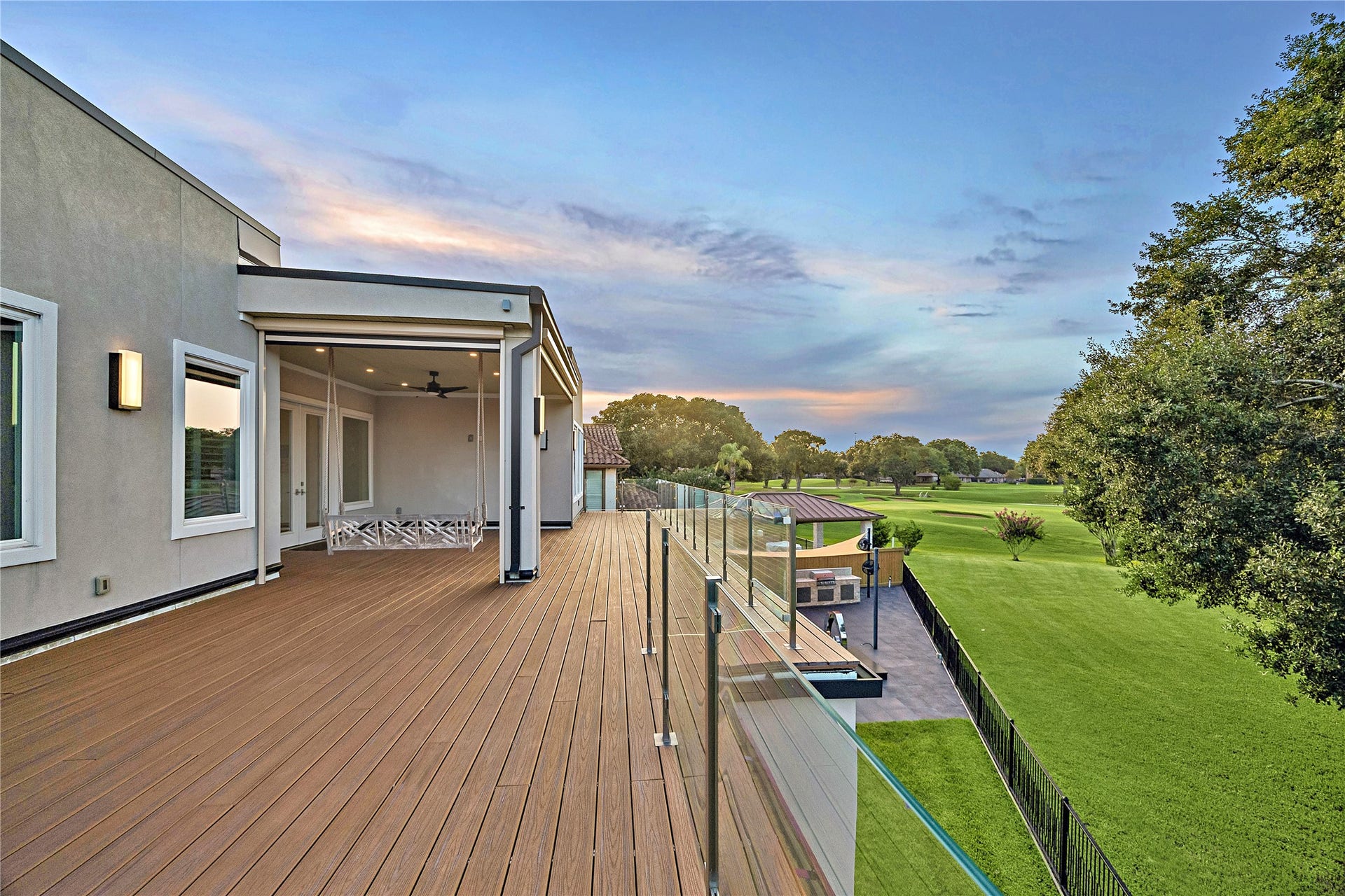 Spectacular 712-square-foot rooftop terrace featuring expansive golf-course views, transparent glass railings, covered seating areas, ceiling fans, and exterior solar screens. Overlooking the mature trees and manicured fairways of Sugar Creek Country Club, this exceptional outdoor retreat offers an unforgettable setting for entertaining and relaxation.