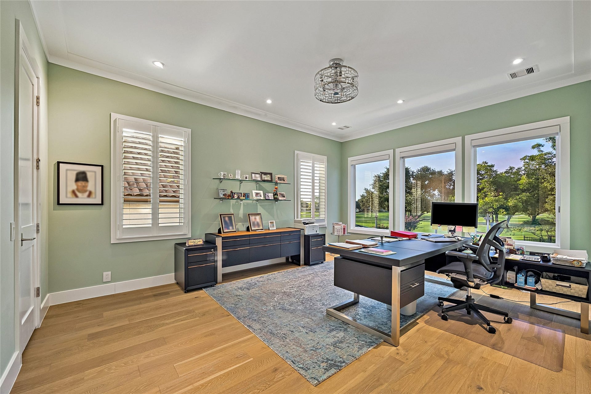A bright dedicated office featuring wood flooring, expansive windows overlooking the fairway, and generous space for desks and storage. The room includes a full closet and potential for future guest or bedroom use, subject to final design, classification, and approvals.