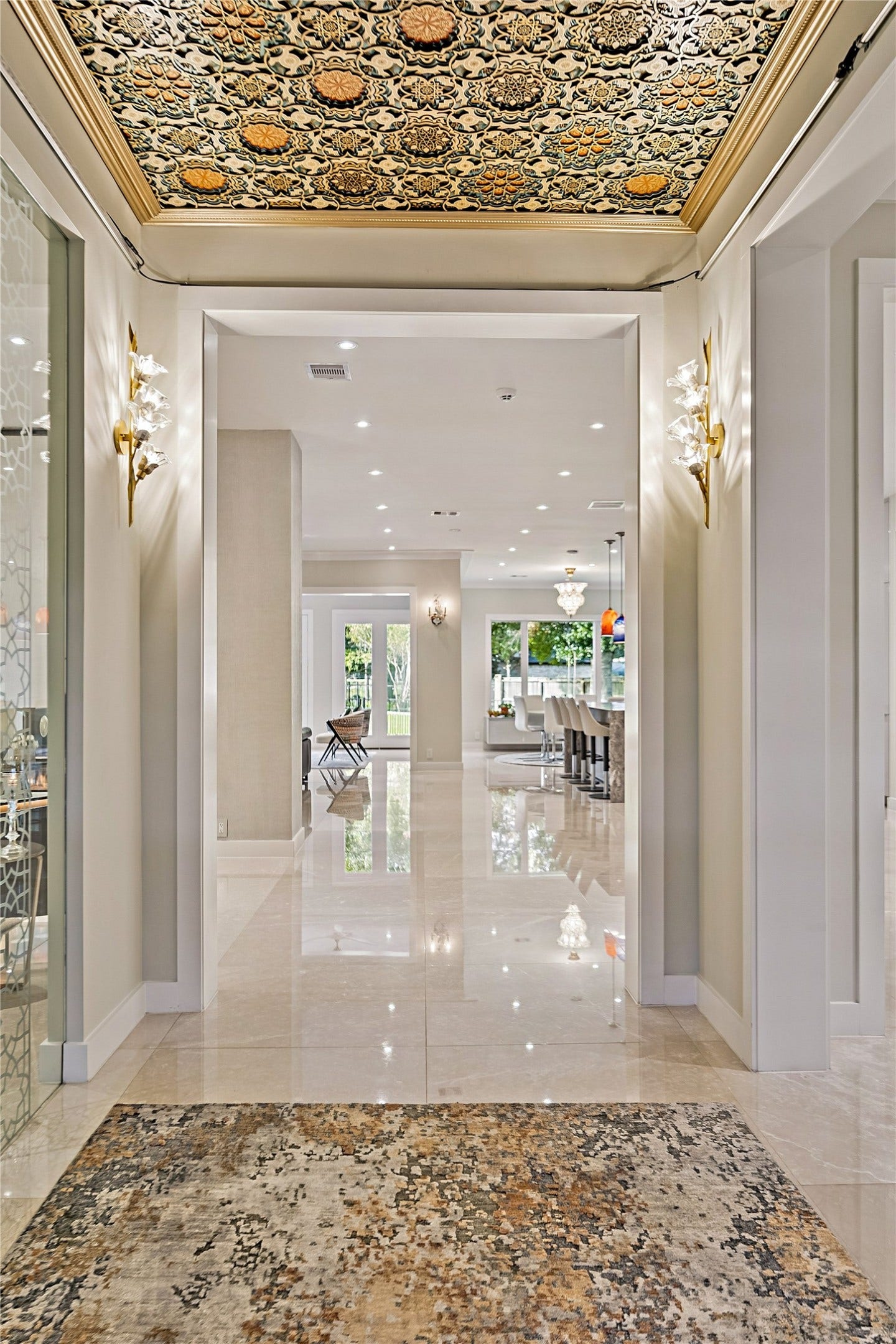 A dramatic entrance gallery featuring polished flooring, intricate decorative ceiling treatments, and elegant architectural transitions. Long interior sight lines introduce the home's expansive formal entertaining spaces.