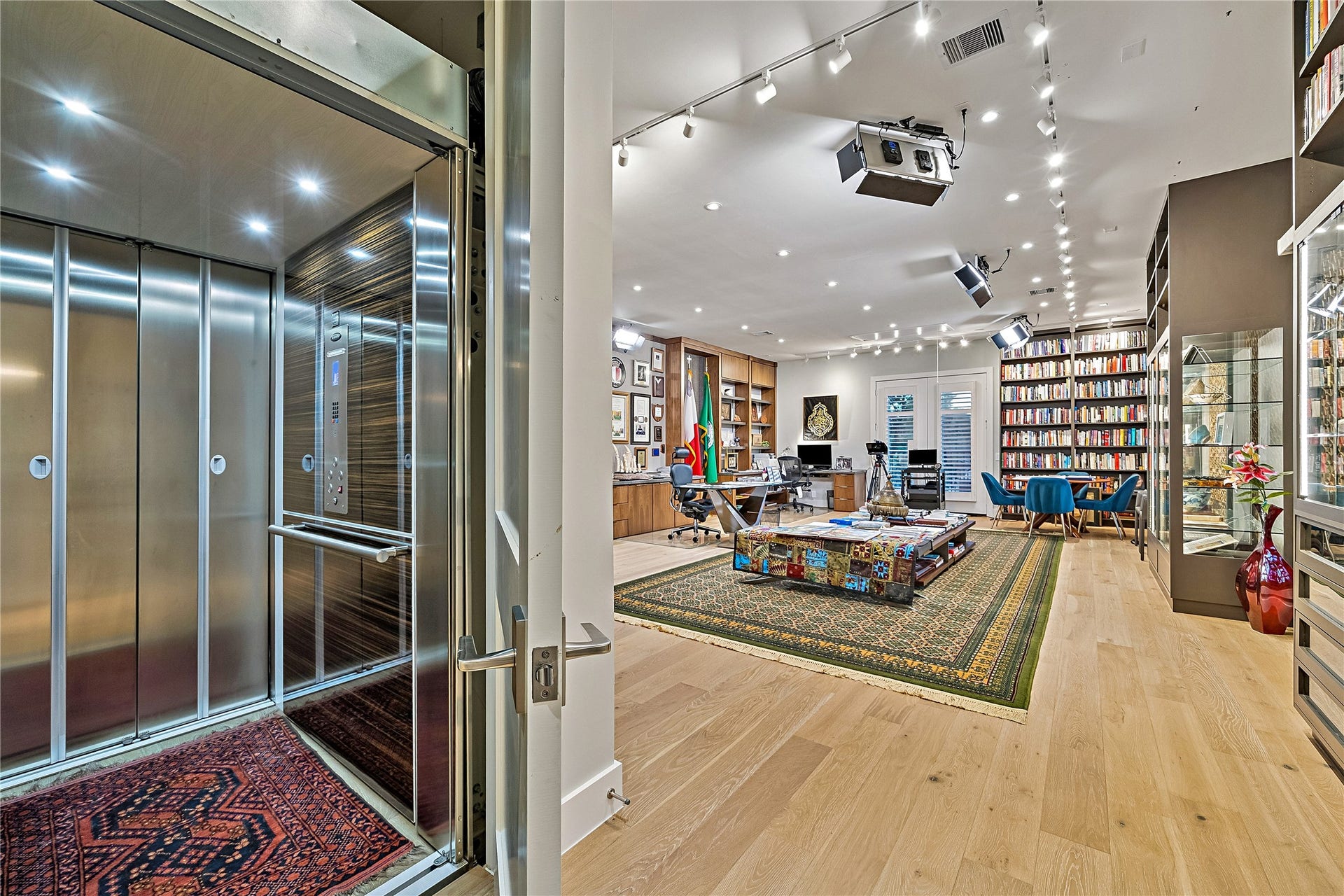 An elegant view of the upper-level library highlighting extensive custom shelving and direct access to the home's private elevator. A thoughtful combination of sophisticated design, functionality, and accessibility between levels.