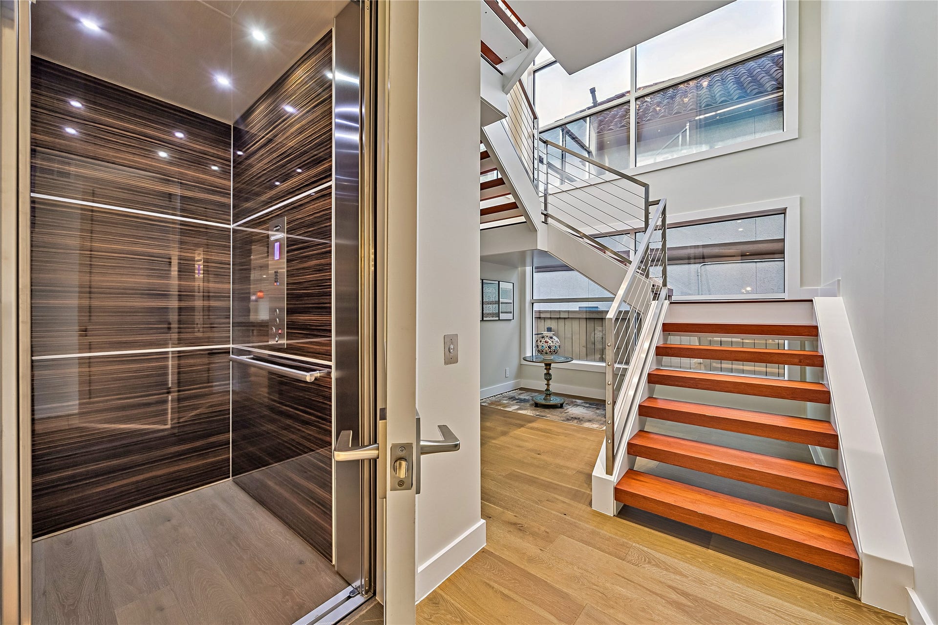 A striking staircase featuring warm wood treads and contemporary railing details provides access to the upper level. The residence also includes a private elevator, offering convenient movement between floors.