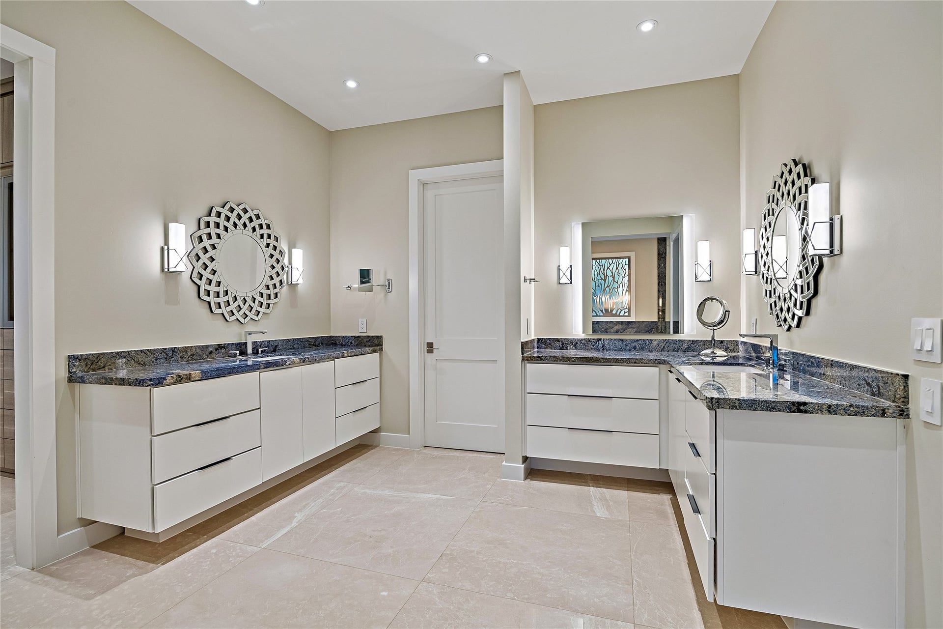 A beautifully appointed primary bathroom featuring separate vanities, generous counter space, decorative mirrors, and refined finishes. The thoughtful layout provides distinct grooming areas within the spacious suite.