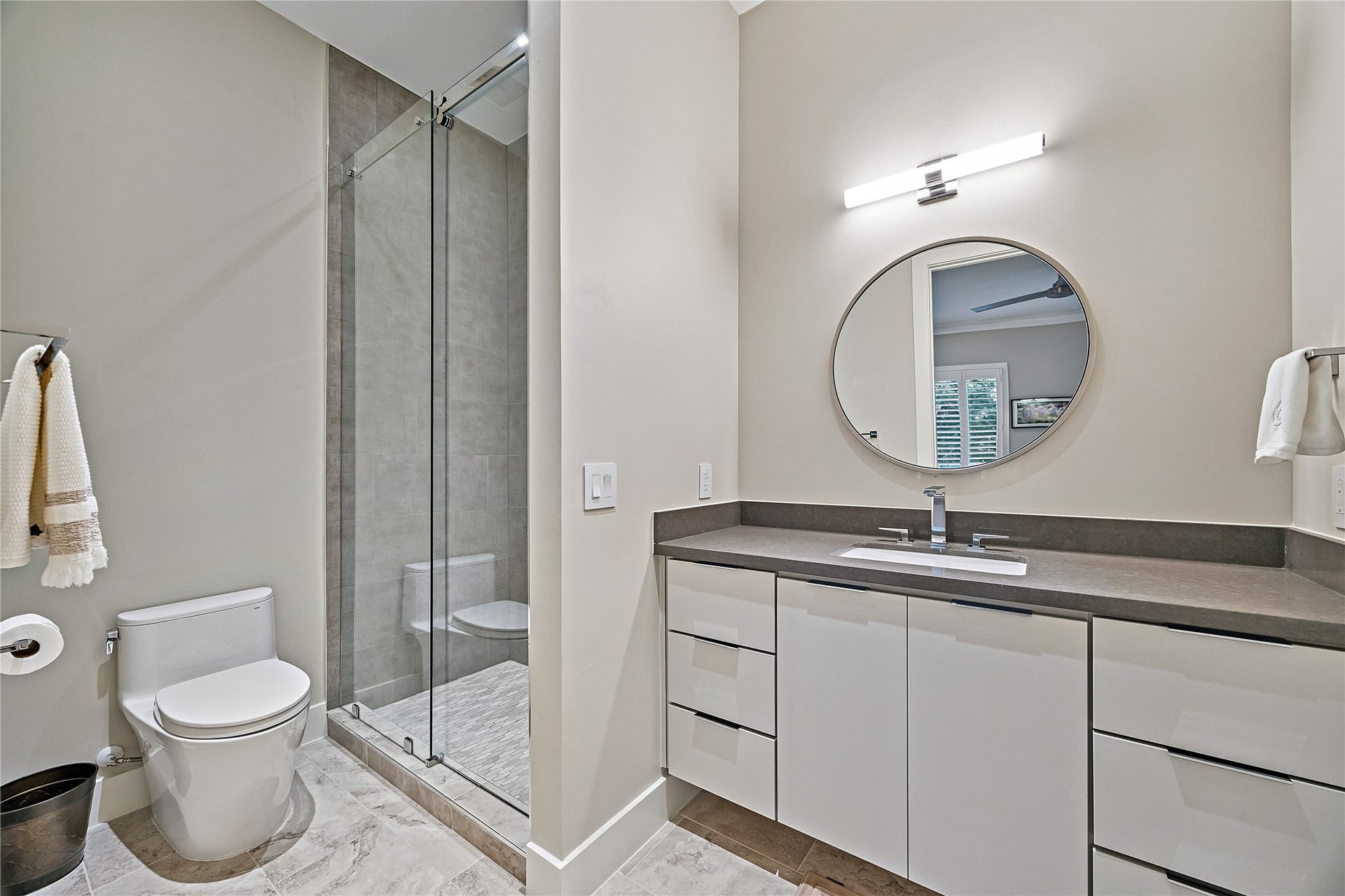 Contemporary bathroom featuring a glass-enclosed shower, streamlined vanity, decorative mirror, and neutral finishes. A thoughtfully designed space complementing the home's secondary bedrooms.
