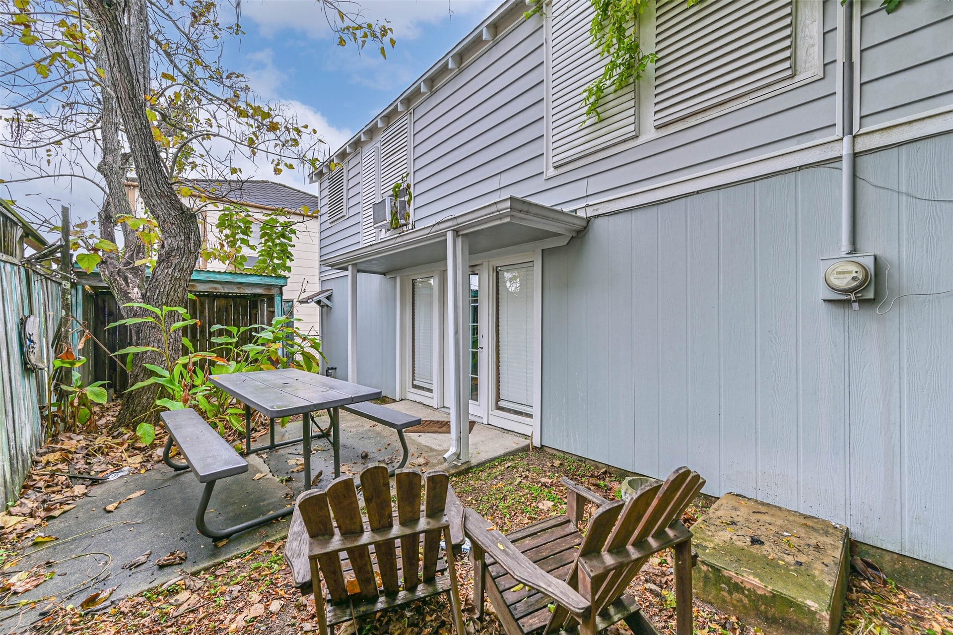 A cozy patio area beside the home, featuring outdoor seating and a shaded setting for relaxing outside.
