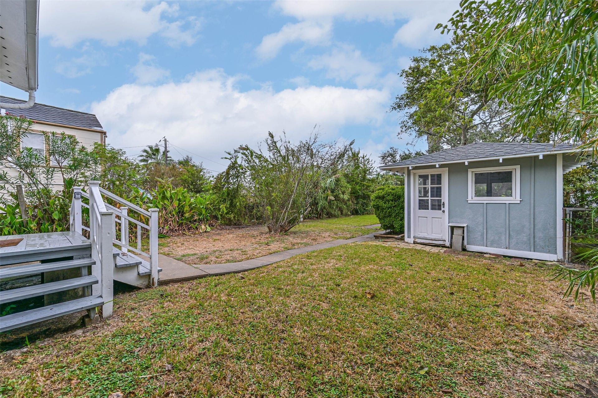 A spacious backyard with mature trees and a raised entry deck, offering room to enjoy the outdoors.
