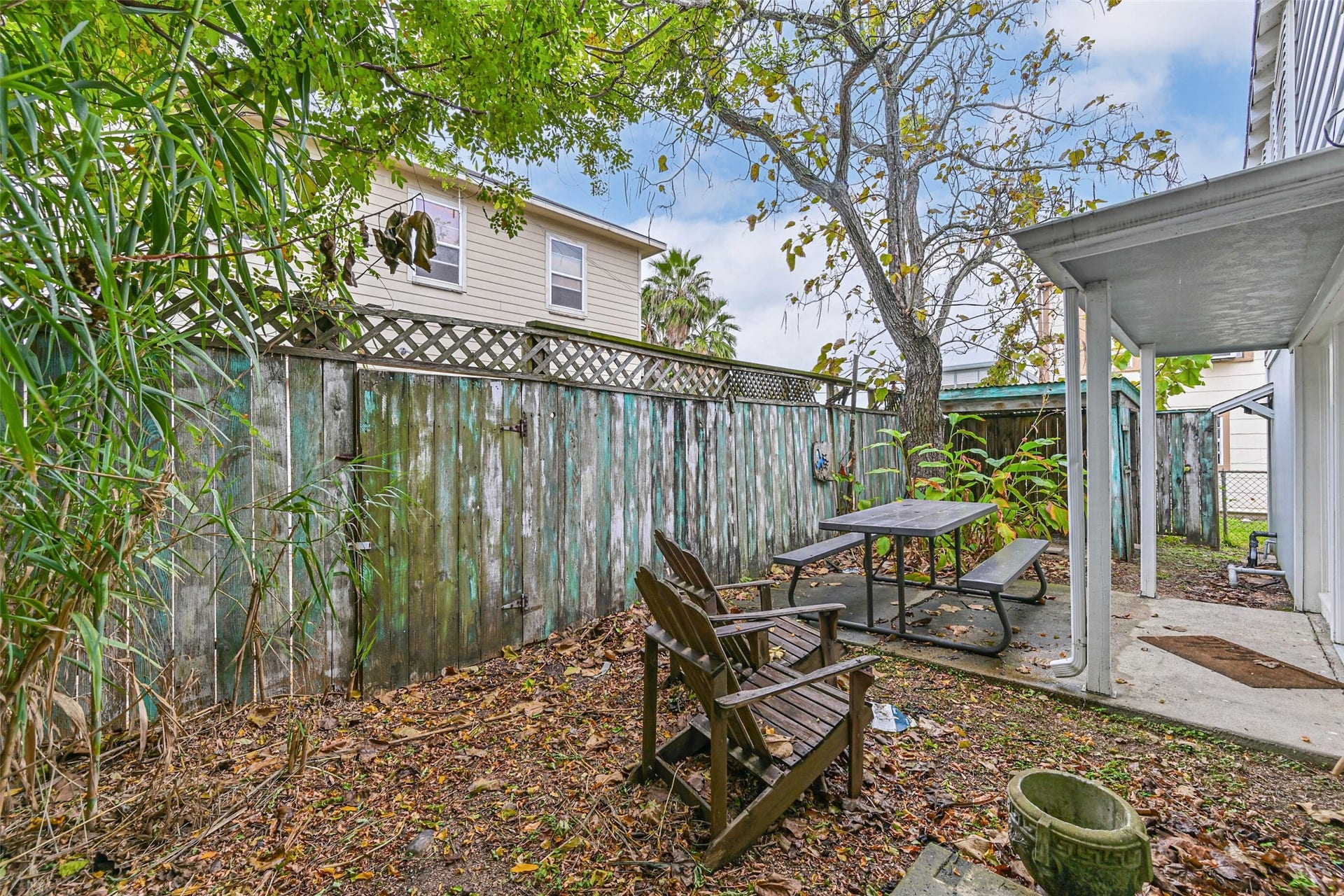 A shaded outdoor area surrounded by mature trees and fencing, creating a private setting for enjoying the fresh air.