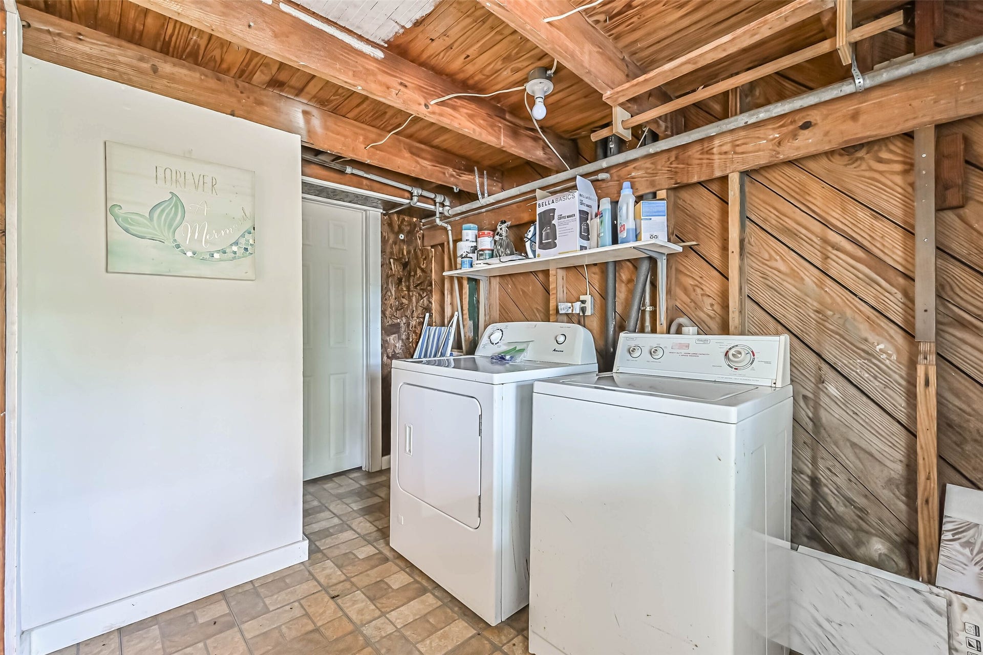 A rustic laundry area with exposed wood walls and ceiling framing, offering a practical space for everyday household tasks.