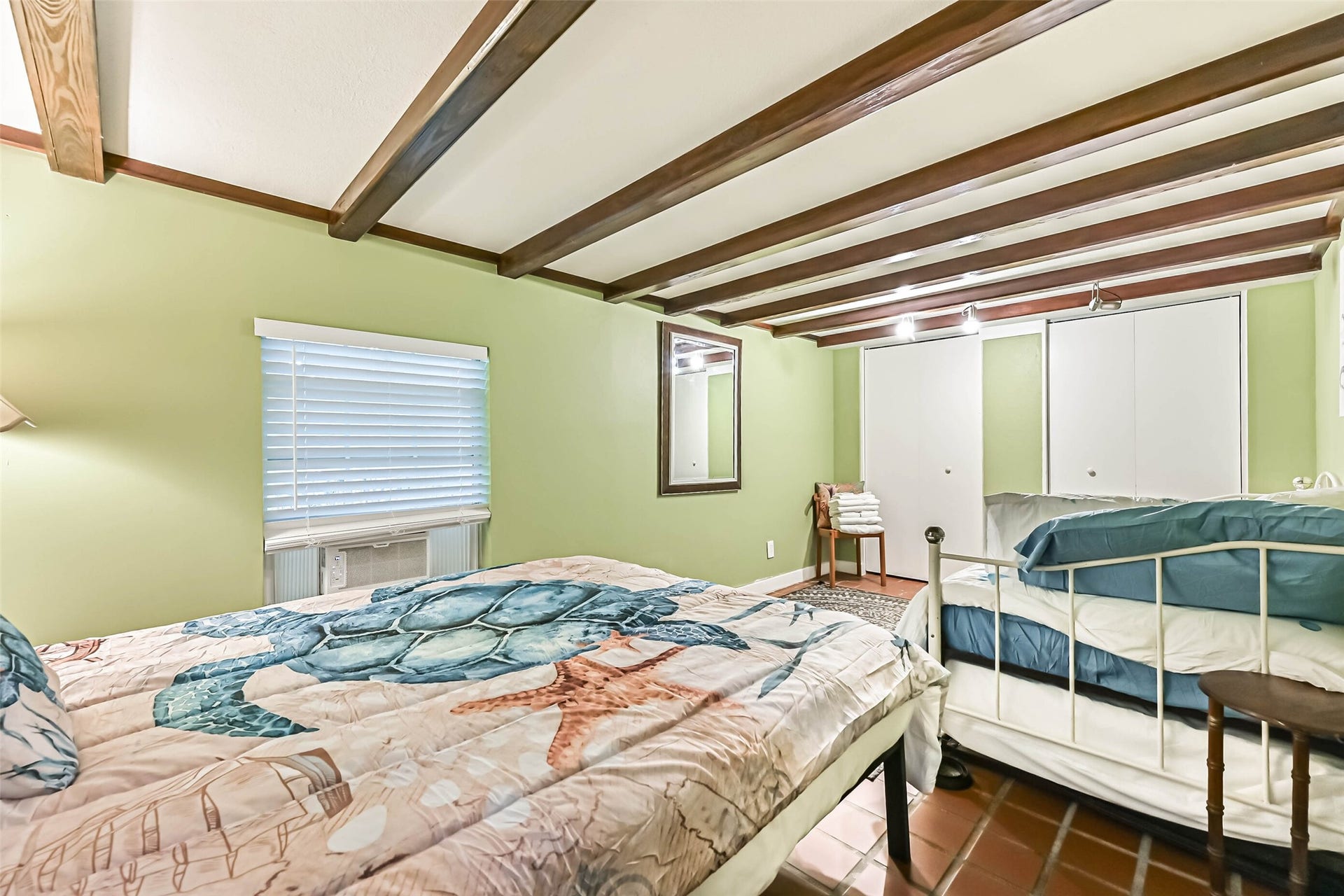 A charming bedroom with exposed wood ceiling beams and two beds, creating a relaxed, coastal-inspired retreat.