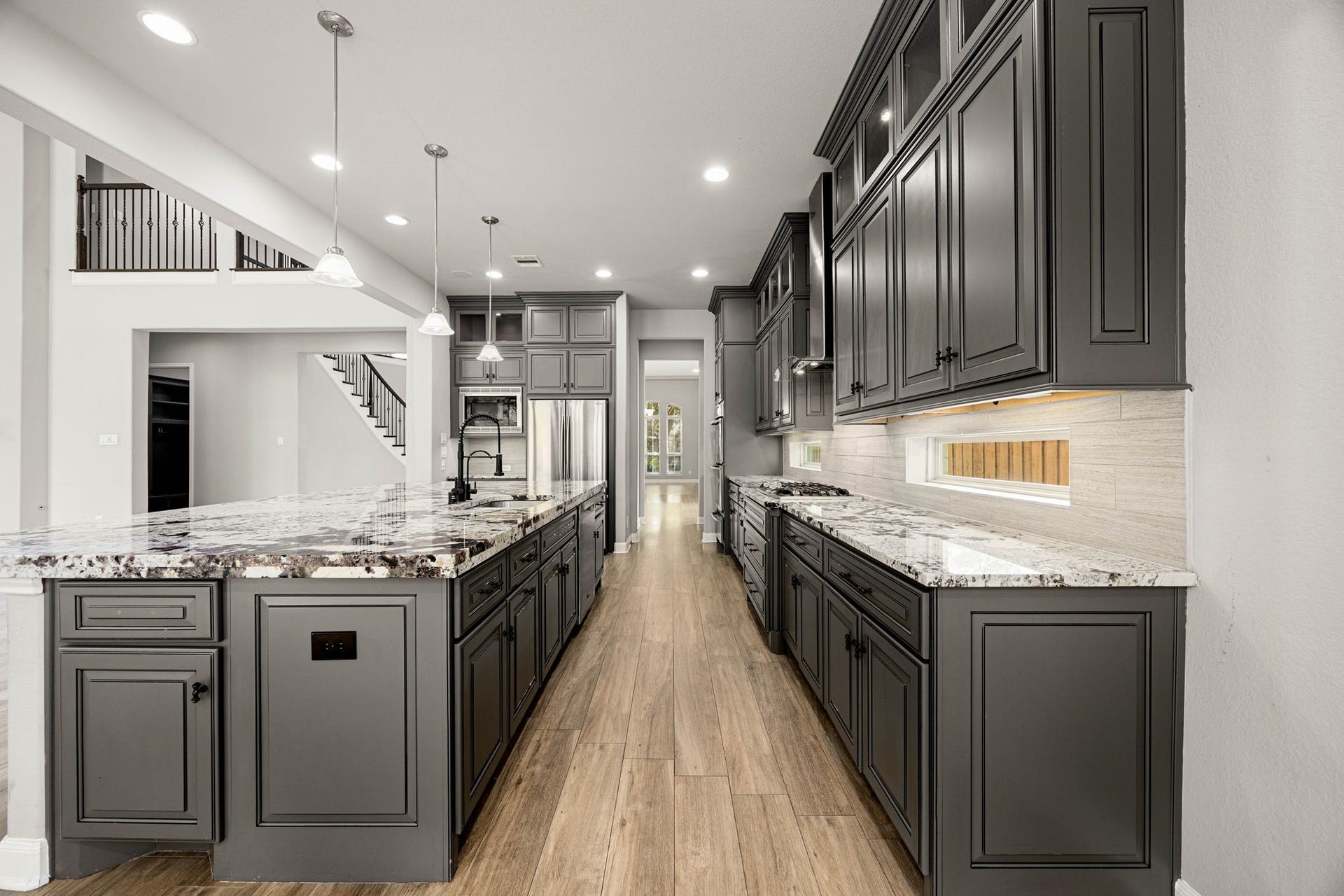 10606 Comeaux Lane, Richmond, TX 77407 A long galley-style layout maximizes counter space in this kitchen, where Marble countertops, dark cabinetry, and a view straight through to the staircase and living area create a well-connected floor plan.