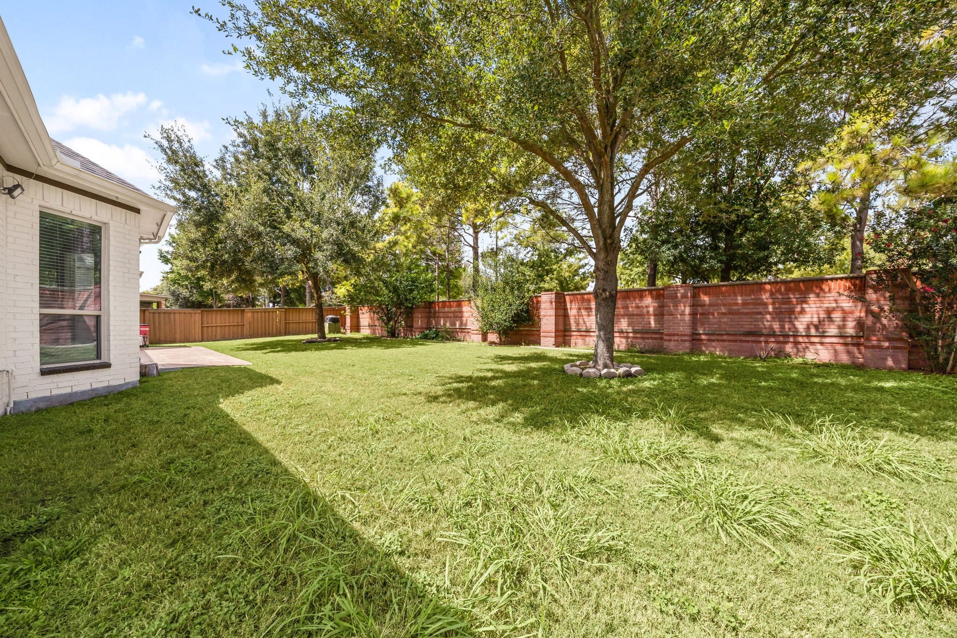 10606 Comeaux Lane, Richmond, TX 77407 Another angle of the fenced backyard highlights its generous size and mature landscaping, with a covered patio just off the home's rear entrance.