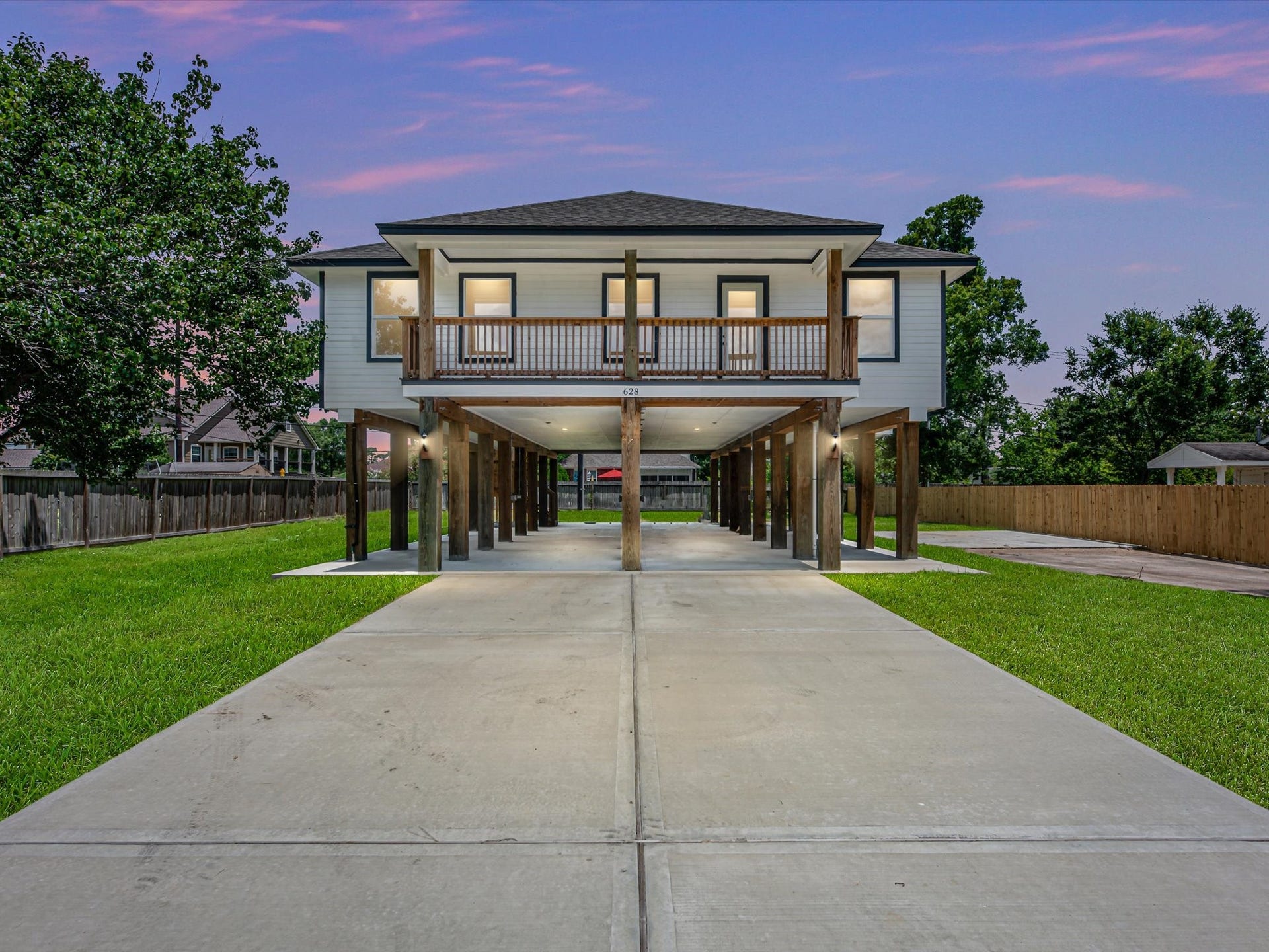 Charming elevated home with a spacious covered balcony, ample parking, and a sleek exterior on oversized lot.