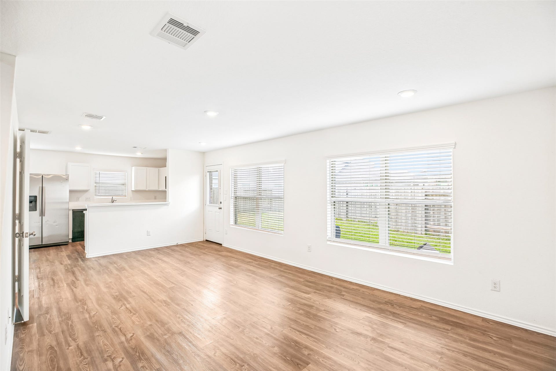 184 Kelly Street, Angleton, TX 77515 Bright open living and dining area with wood-look flooring, wide windows, and a connected kitchen view.
