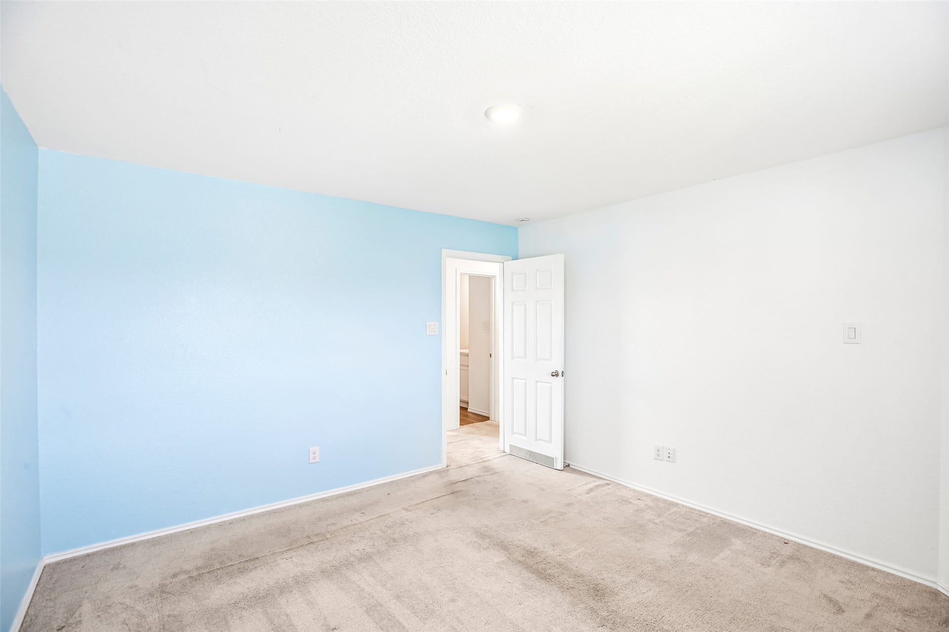 184 Kelly Street, Angleton, TX 77515 Empty carpeted room with a blue accent wall and open doorway.
