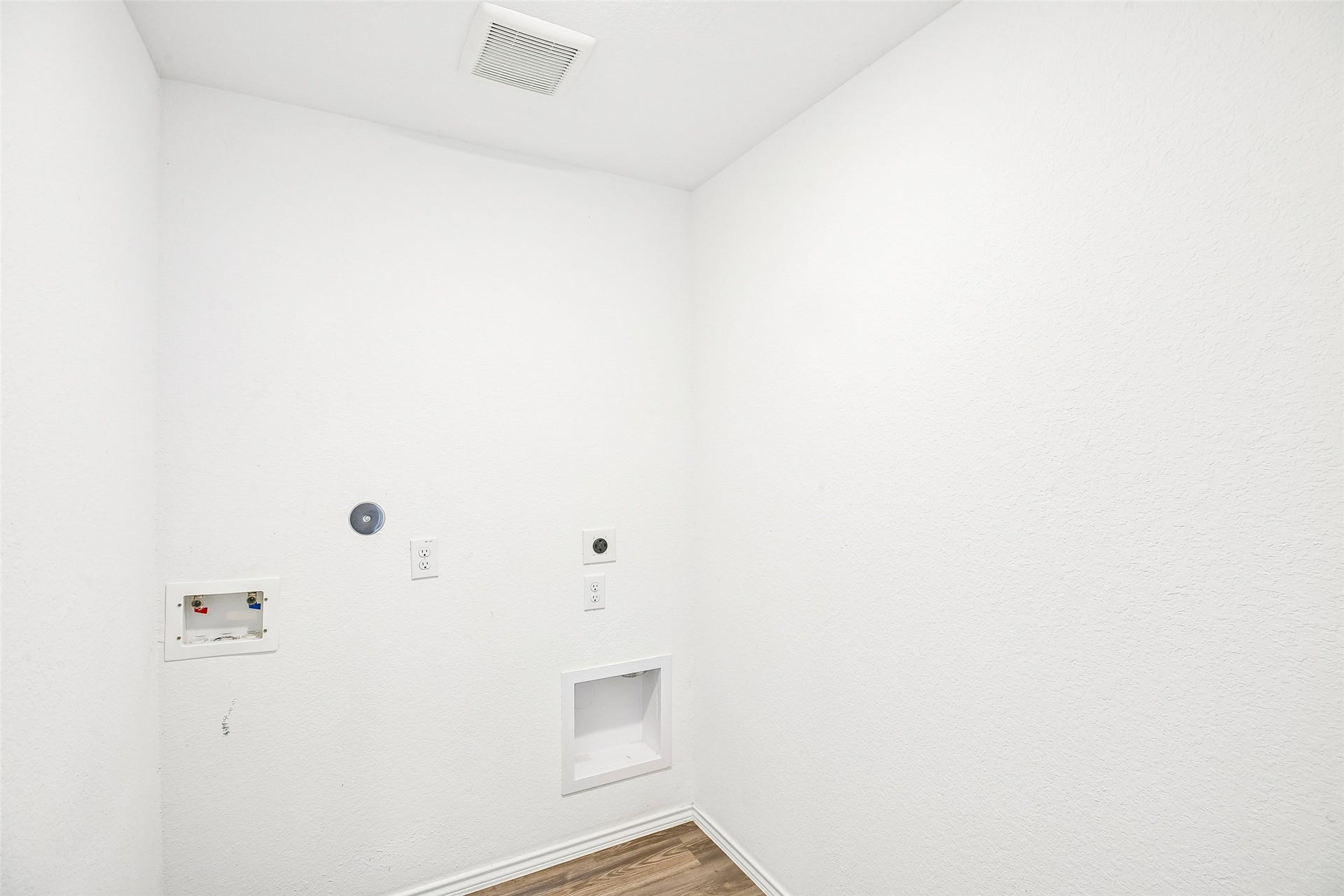 184 Kelly Street, Angleton, TX 77515 Empty interior utility-area corner with textured white walls, wall outlets and service boxes, a ceiling vent, and wood-look flooring.