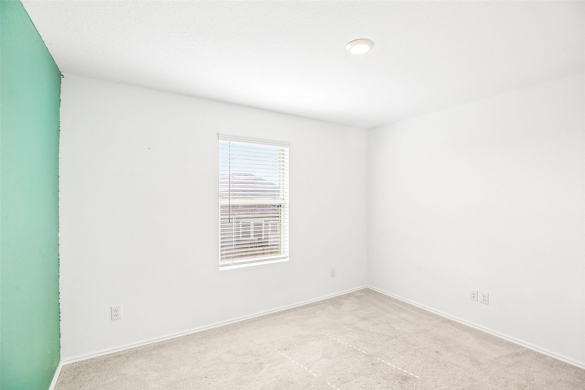184 Kelly Street, Angleton, TX 77515 Empty carpeted interior room with a window and blinds, light walls, and a turquoise accent wall at left.