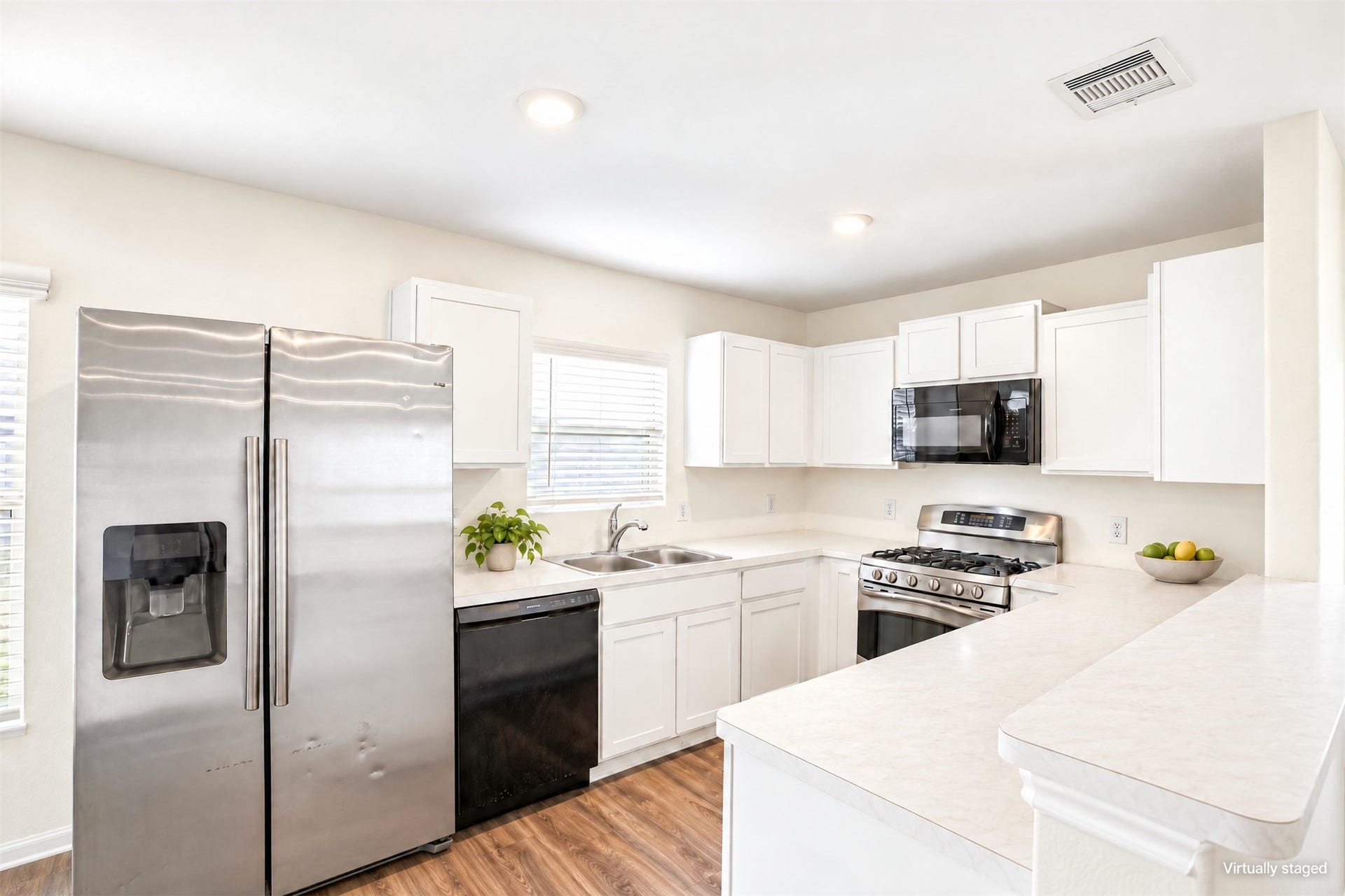 184 Kelly Street, Angleton, TX 77515 Bright kitchen with white cabinetry, light counters, stainless appliances, and wood-look flooring.