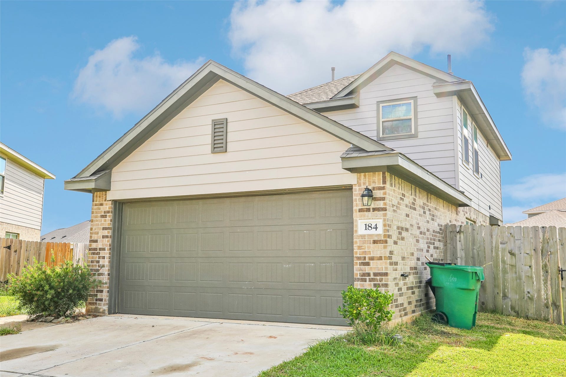 184 Kelly Street, Angleton, TX 77515 Front exterior view showing the attached garage, brick-and-siding facade, driveway, lawn, fencing, and landscaping.