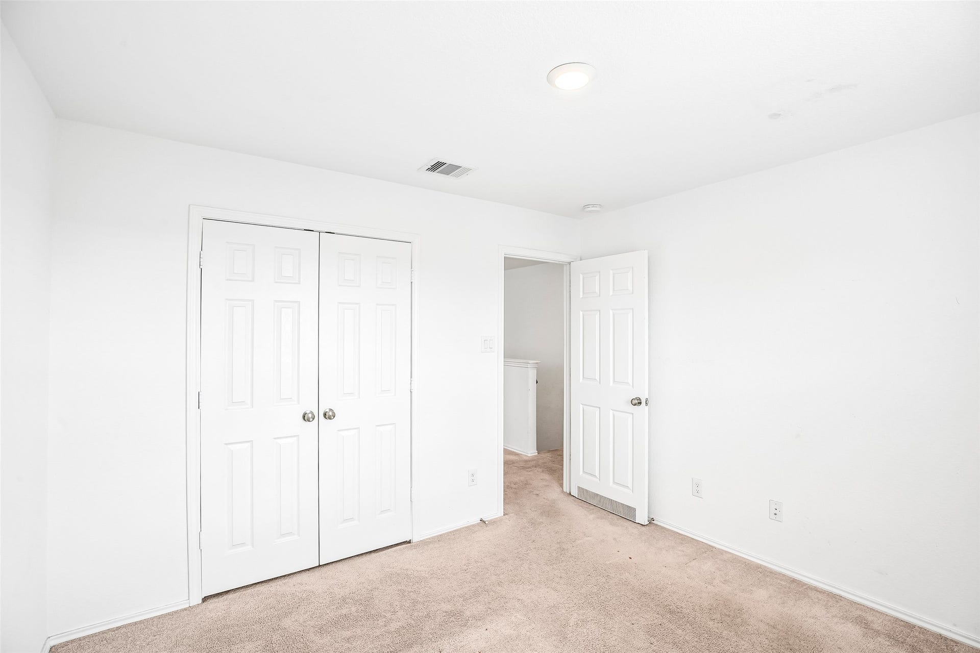 184 Kelly Street, Angleton, TX 77515 Empty carpeted interior room with double closet doors, an open hall doorway, light walls, and a ceiling vent.