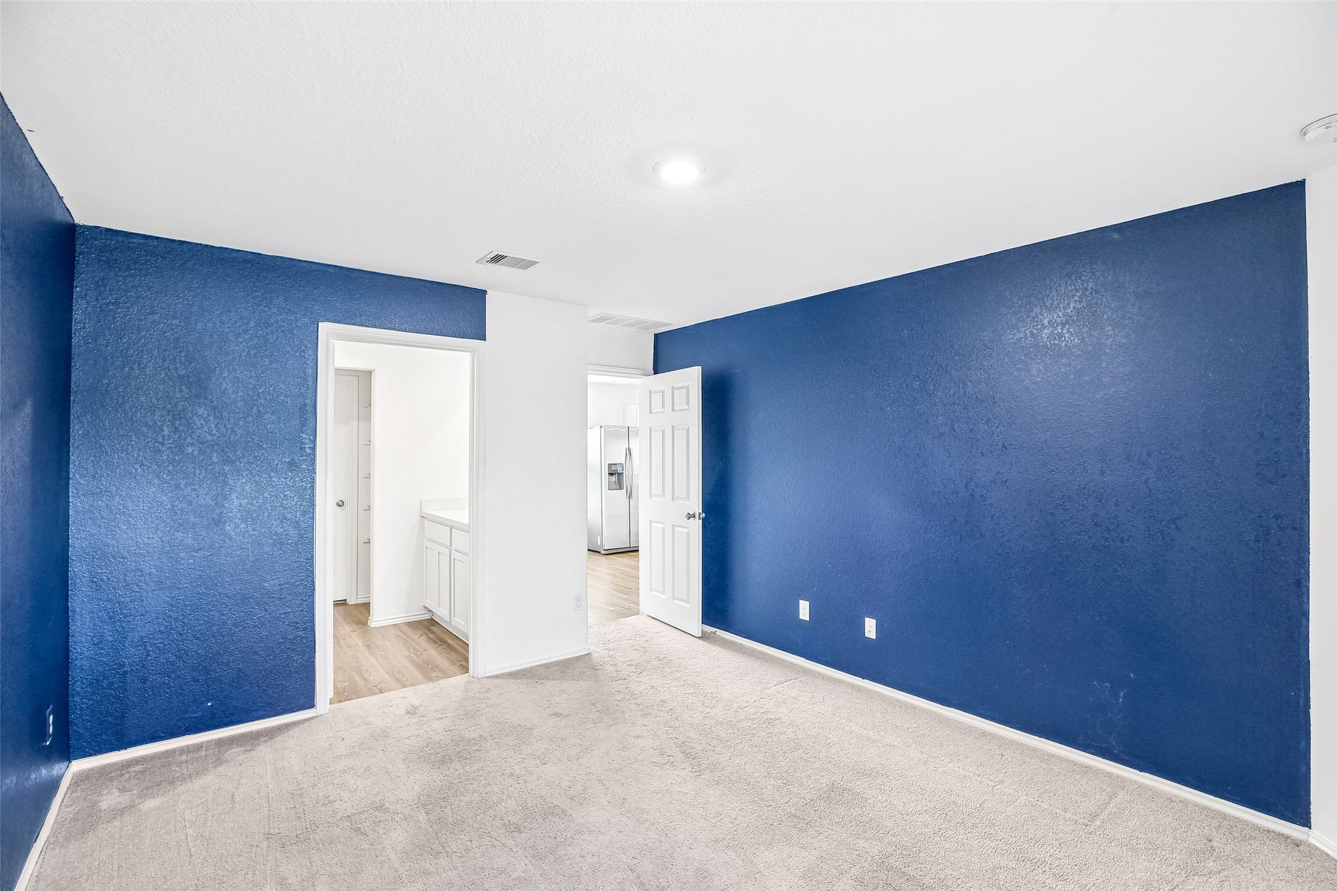 184 Kelly Street, Angleton, TX 77515 Empty carpeted room with blue accent walls, white trim and two open doorways to adjacent areas.