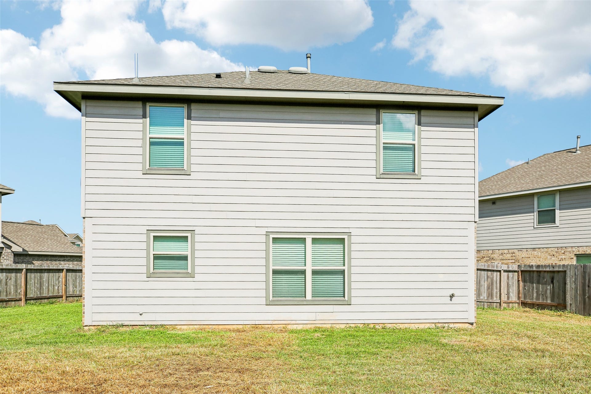 184 Kelly Street, Angleton, TX 77515 Rear exterior elevation viewed from the backyard, showing the home's siding, windows, fencing, and yard.