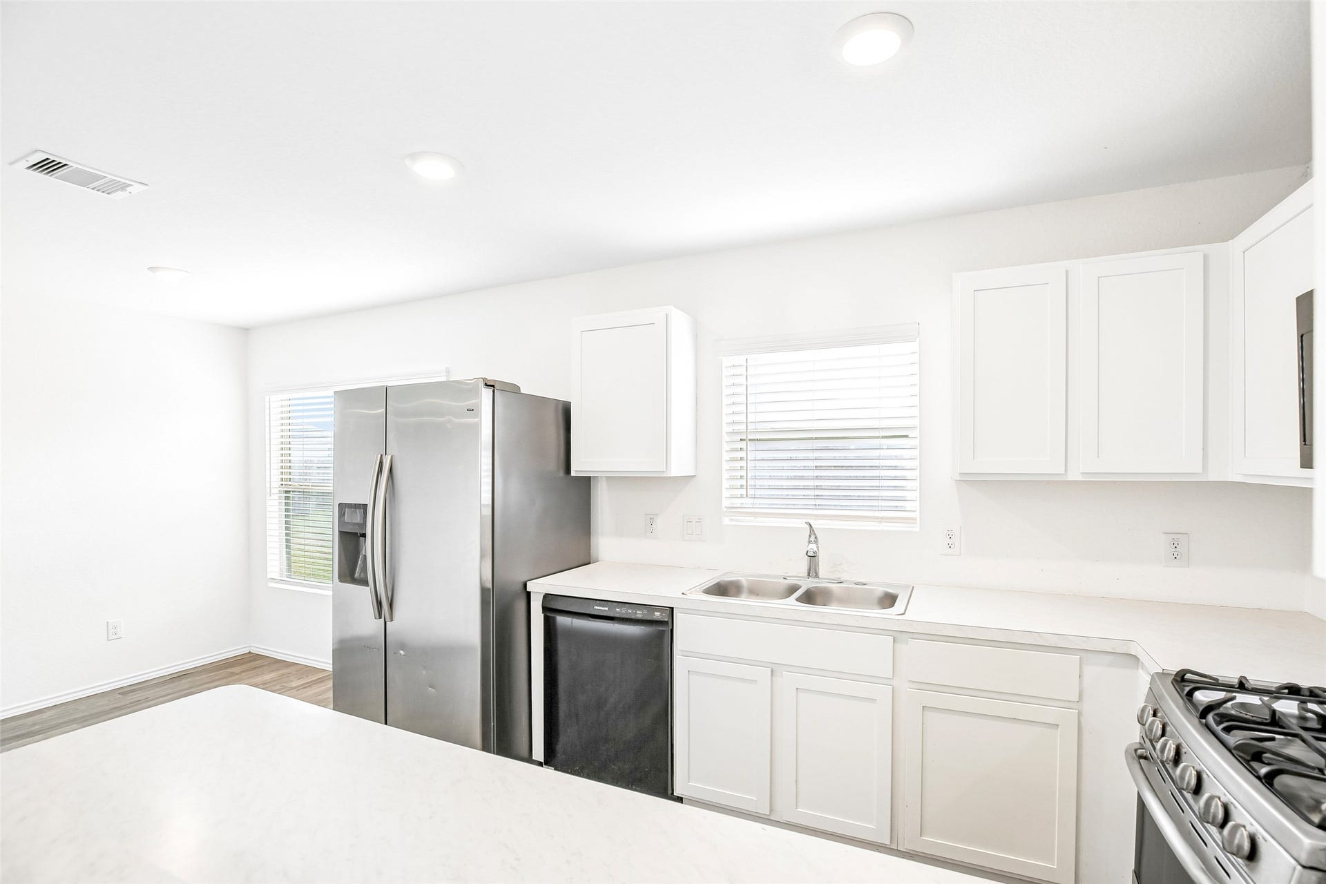 184 Kelly Street, Angleton, TX 77515 Kitchen view showing white cabinetry, stainless appliances, sink, counters, and the adjacent dining area.