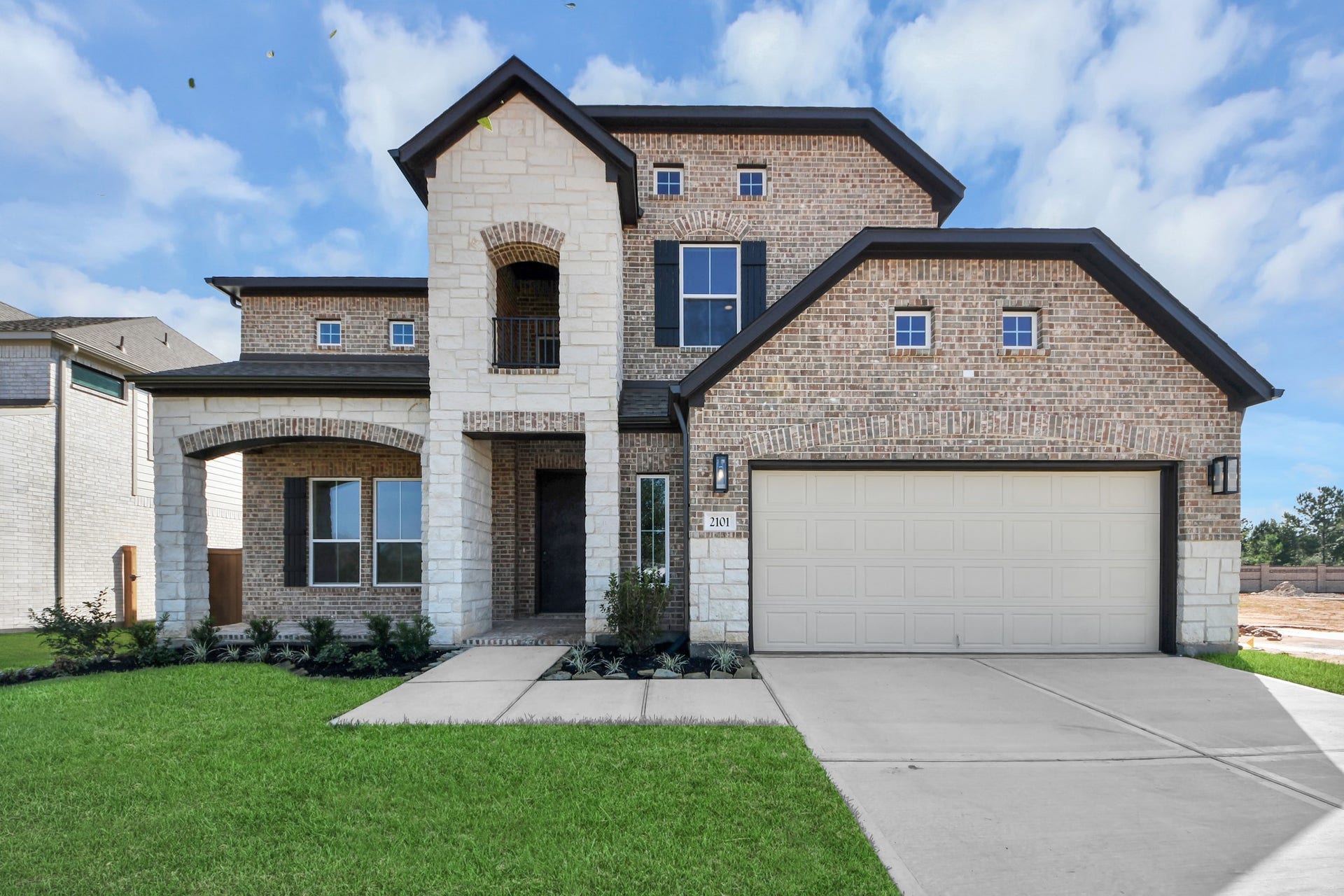 This home boasts lush green grass and meticulous landscaping. Its premium elevation showcases an exquisite blend of brick and stone features, complemented by modern coach lighting