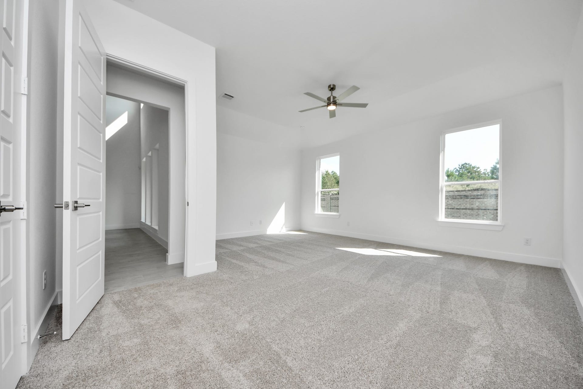 Escape and relax in the exquisite primary suite, a haven to unwind after a long day. The spacious room, located on first floor, boasts plush carpeting, soothing paint tones, high ceilings, and expansive windows adorned with privacy blinds.