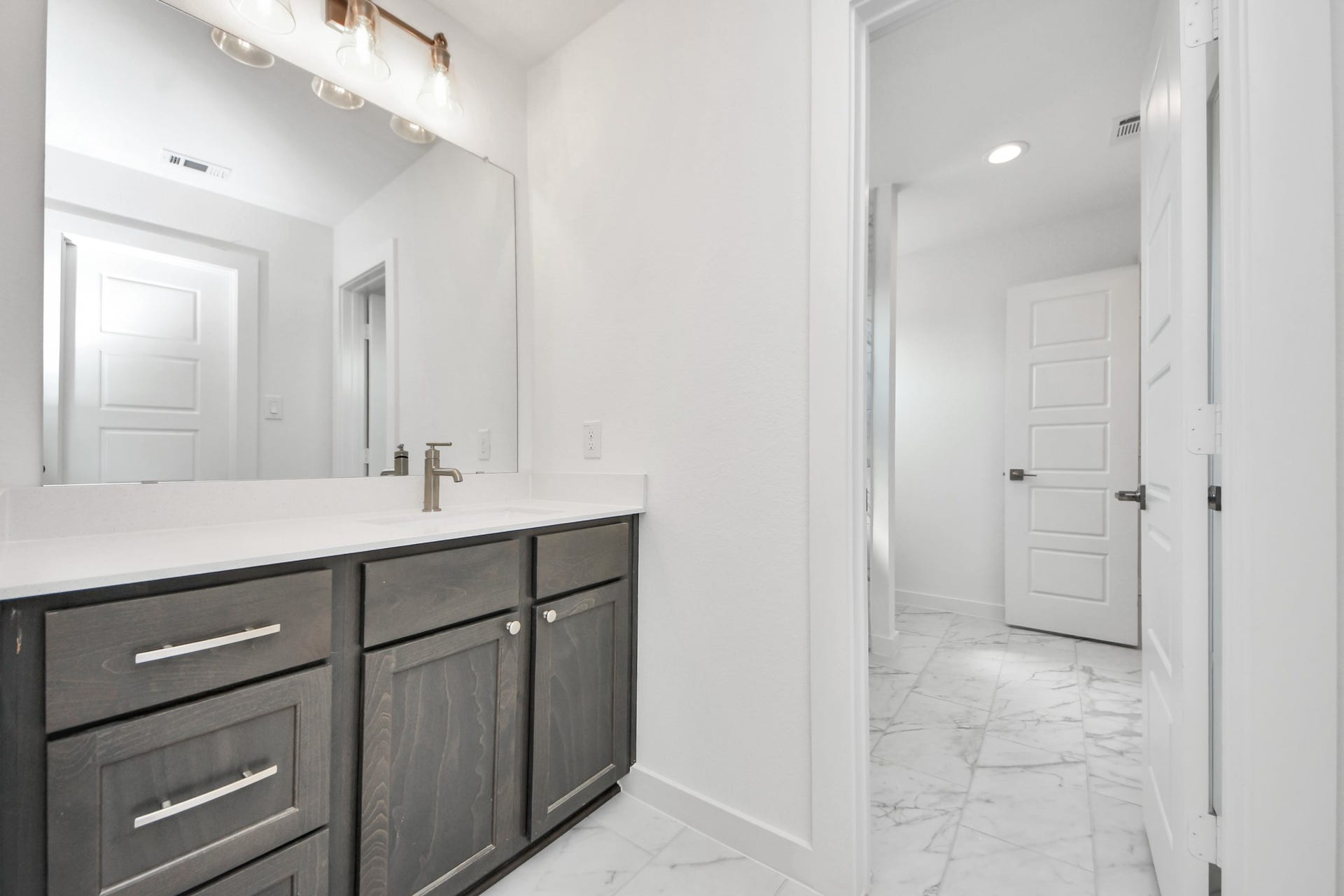 Secondary bath features tile flooring, walk-in shower with tile surround, light stained wood cabinets, beautiful light countertop.