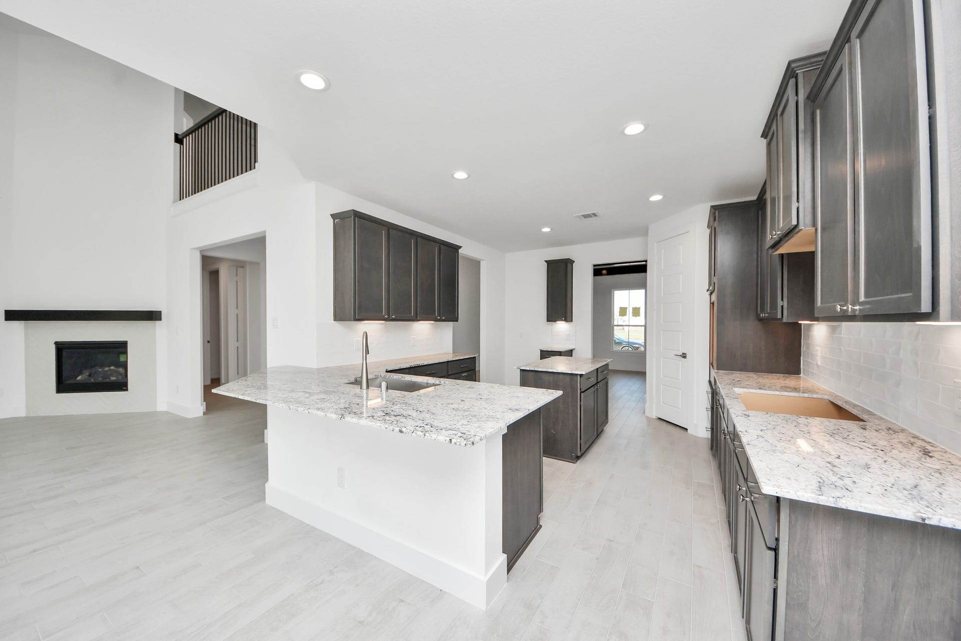 This generously spacious kitchen is a dream realized! With a massive granite island, high ceilings, soft close cabinets, granite countertops, stainless steel appliances, a sleek tile backsplash, recessed lighting, and an extended counter area, it offers both style and practicality. All this opens up to the expansive family room, creating a perfect hub for gatherings.