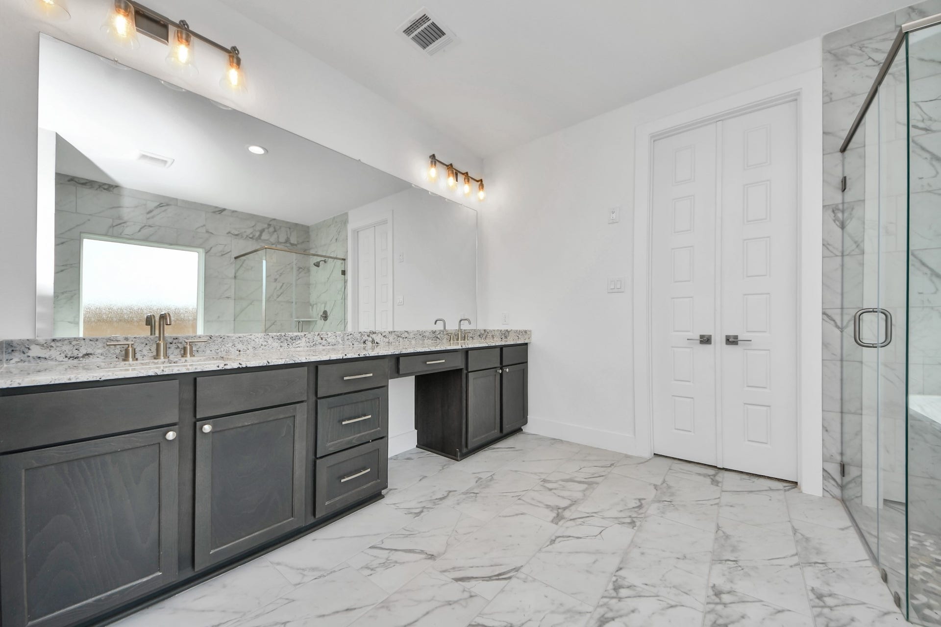 Elevate your daily routine at the elegant vanity, now equipped with double sinks, light countertops, modern hardware, and beautiful vanity lights.