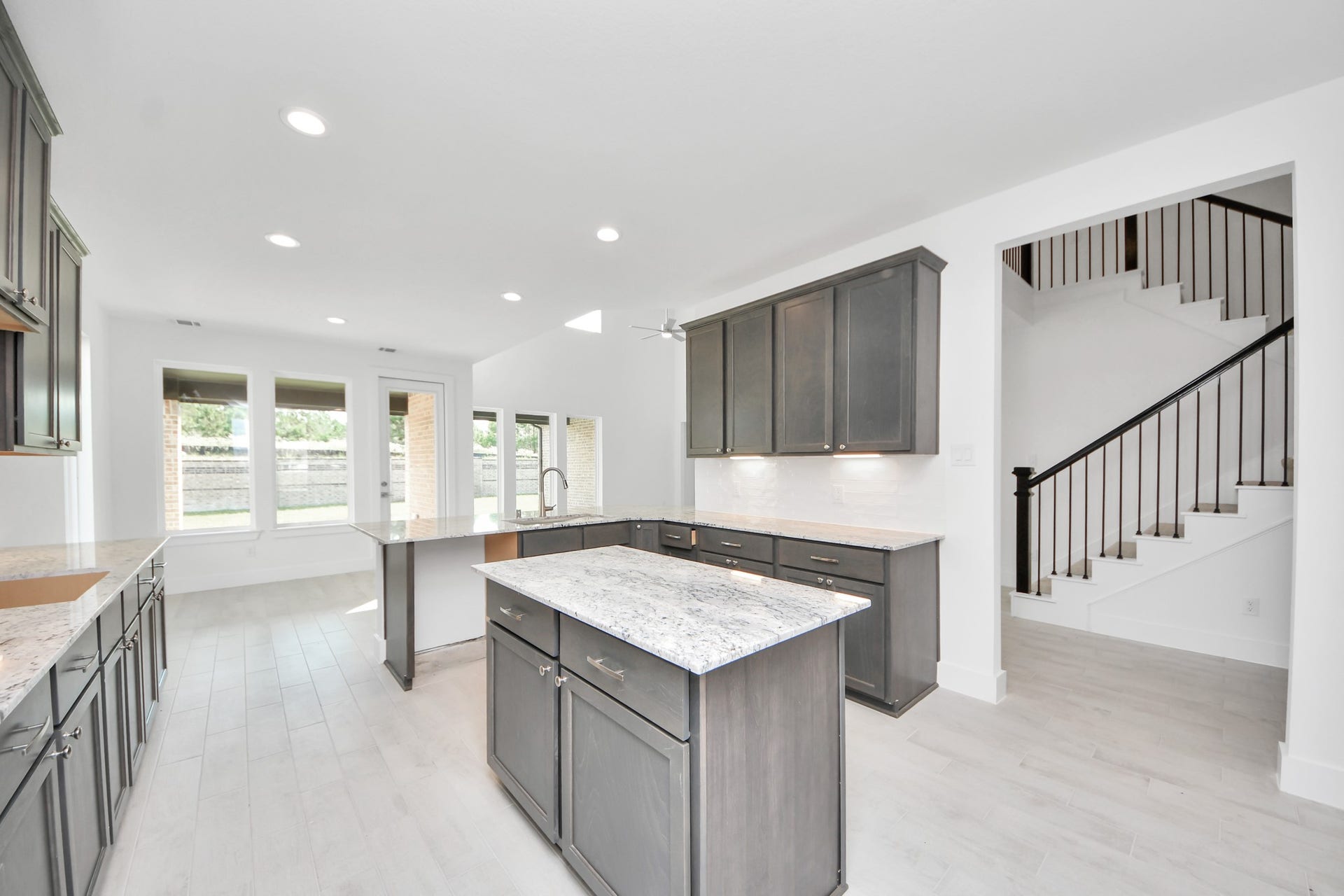 Step into a dream realized with this generously spacious kitchen! A massive granite island takes center stage, complemented by high ceilings and soft-close cabinets. The granite countertops, stainless steel appliances, sleek tile backsplash, and recessed lighting complete the elegant design.