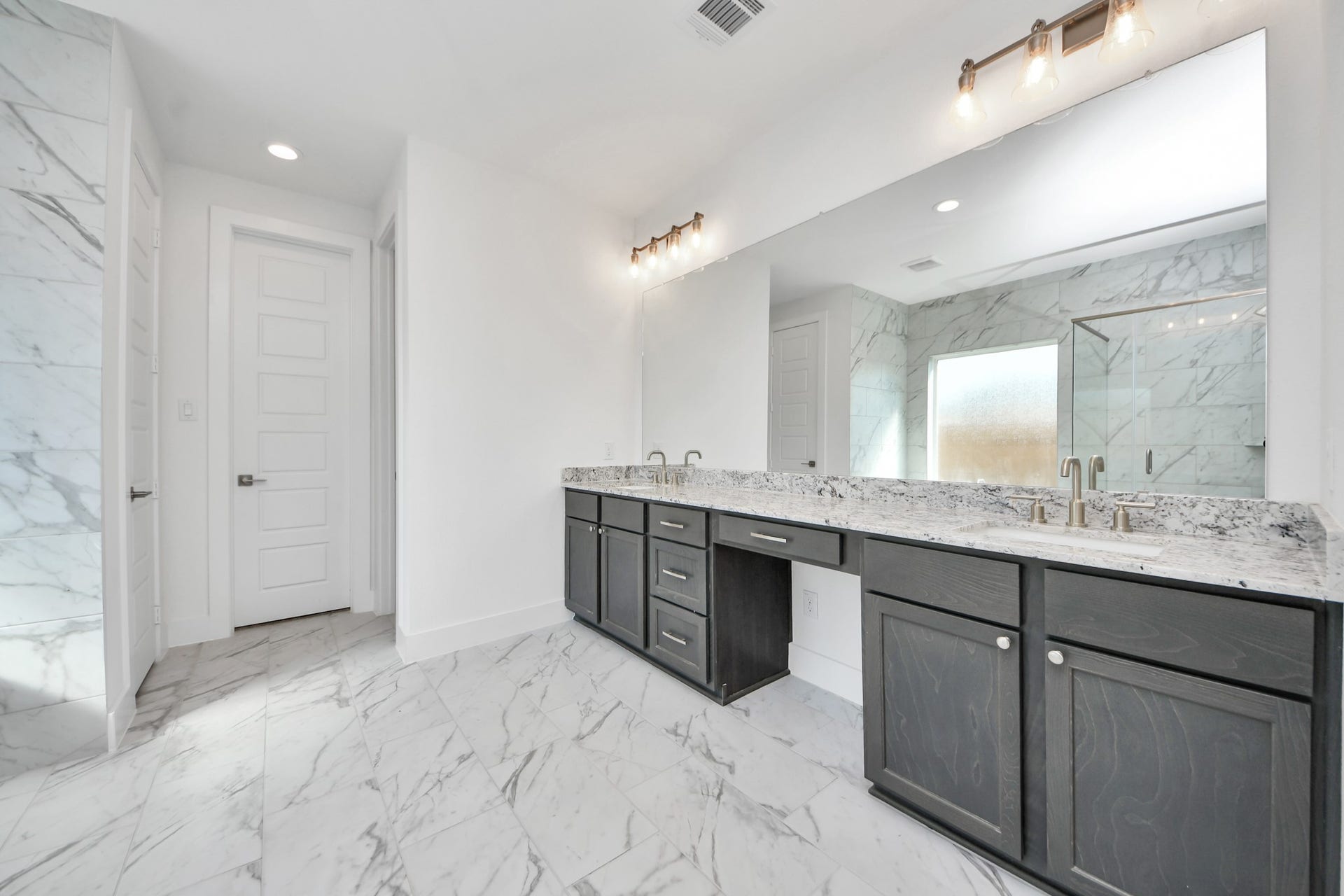 Escape to a spa-like oasis in this primary bathroom. Enjoy a walk-in shower with tile surround, a separate garden tub with custom detailing, and an elegant vanity featuring light countertops, modern hardware, and beautiful vanity lights. Experience luxury and relaxation in every detail.