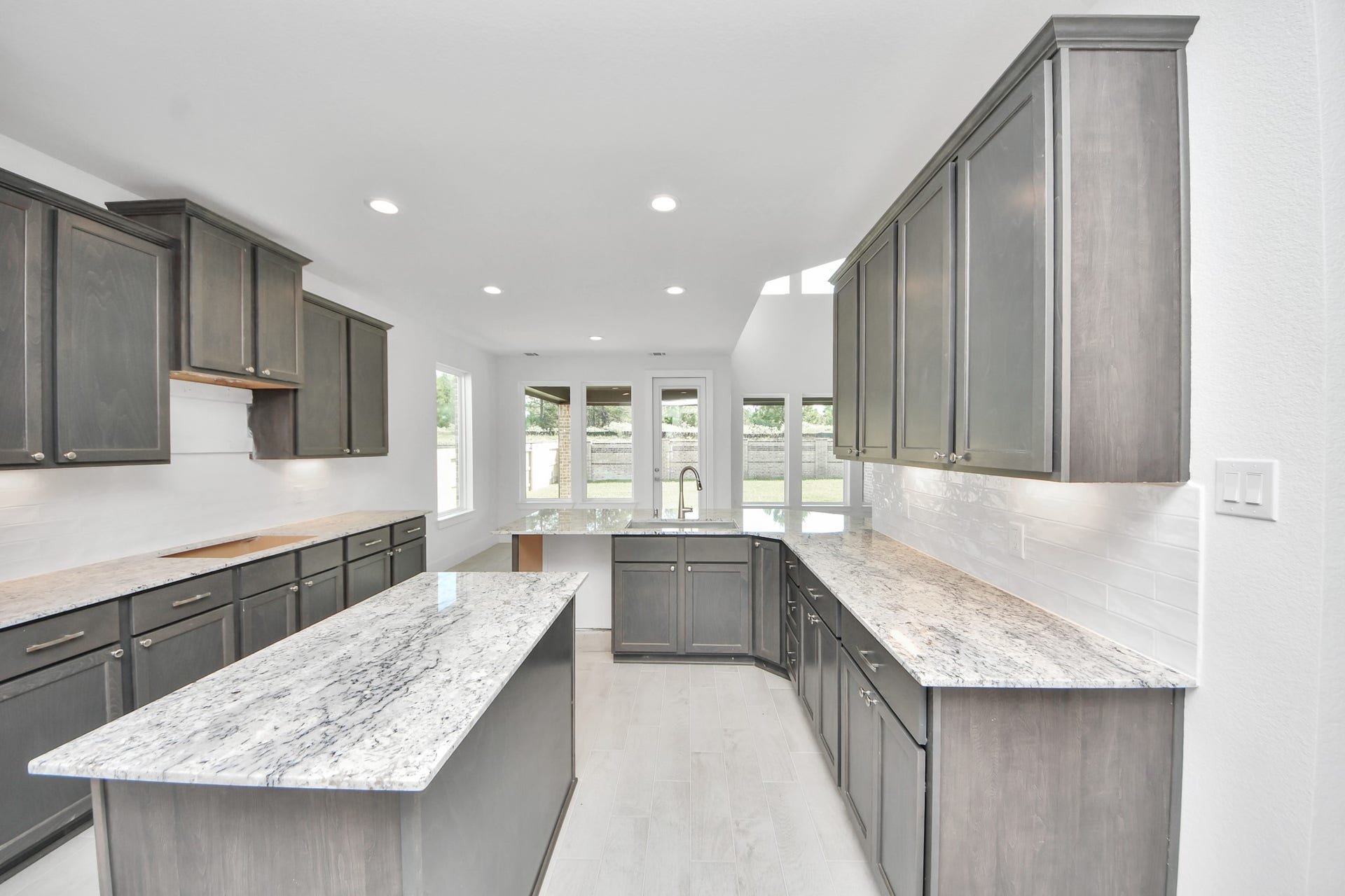 This kitchen is by far any chefs dream! This spacious kitchen features high ceilings, stained wood cabinets, granite countertop, SS appliances, modern tile backsplash, recessed lighting, extended counter space, granite kitchen island with double sink, and space for breakfast bar, and a walk-in pantry all overlooking your huge family room.