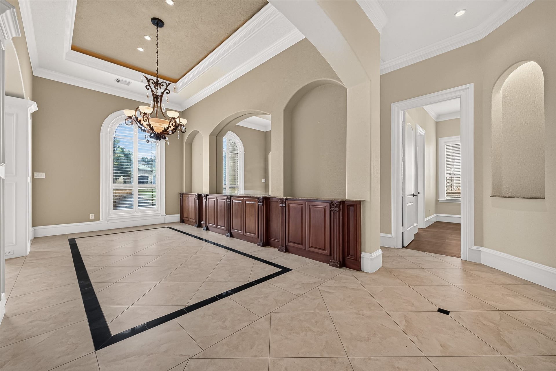 4011 Westerdale Drive, Fulshear, TX 77441 The formal dining room is a true showpiece, highlighted by an elegant tray ceiling, a dazzling statement chandelier, and decorative accent floor tile. A custom built-in buffet spanning an entire wall offers both beauty and function, while graceful arched niches and an oversized mirror enhance the rooms depth and sense of grandeur creating an unforgettable setting for refined entertaining.