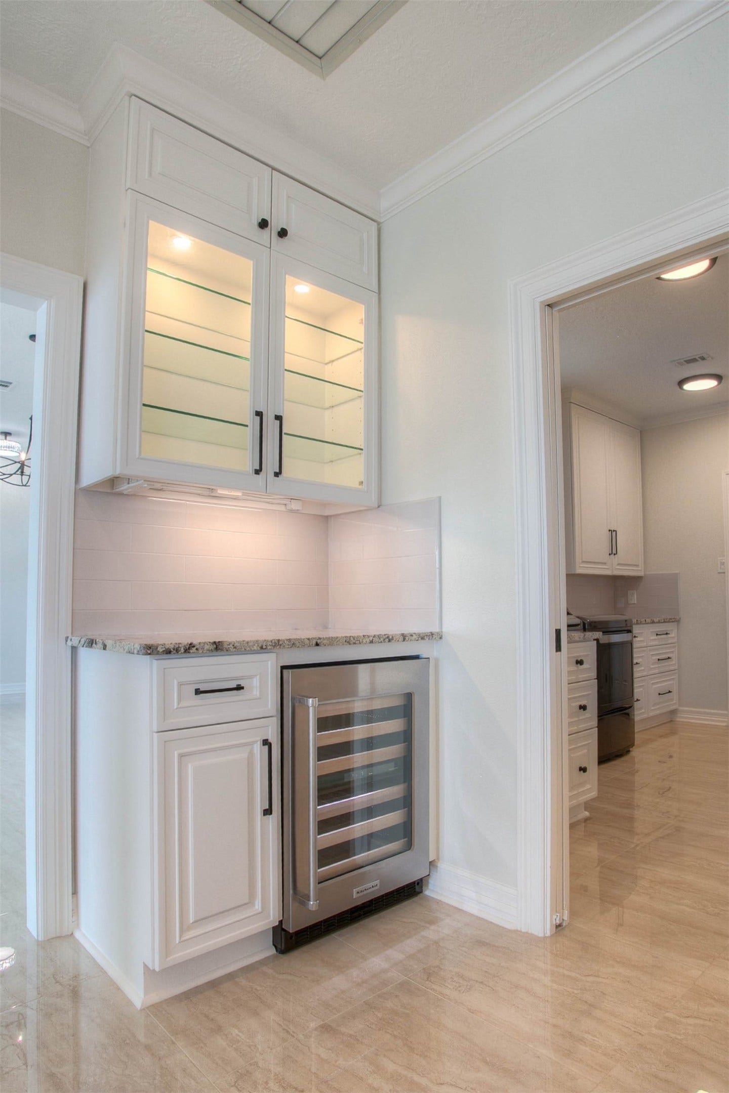 12092 Sagittarius Drive E, Willis, TX 77318 Elegant kitchen nook featuring a wine cooler, glass-front cabinetry, and sleek granite countertops, seamlessly flowing into a bright kitchen area.