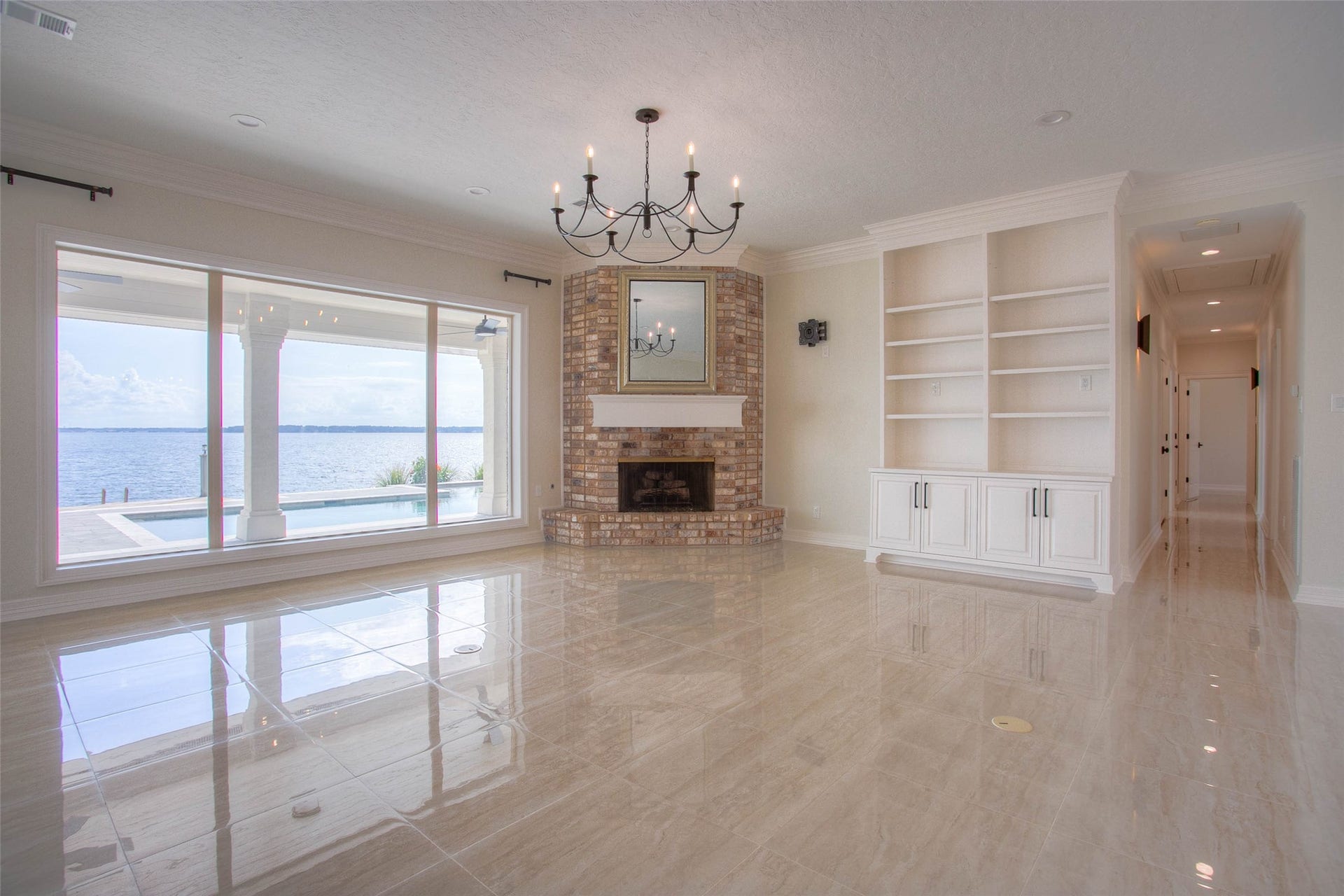 12092 Sagittarius Drive E, Willis, TX 77318 Experience stunning waterfront views in this elegant living room featuring a cozy brick fireplace, built-in shelving, and gleaming tile floors.