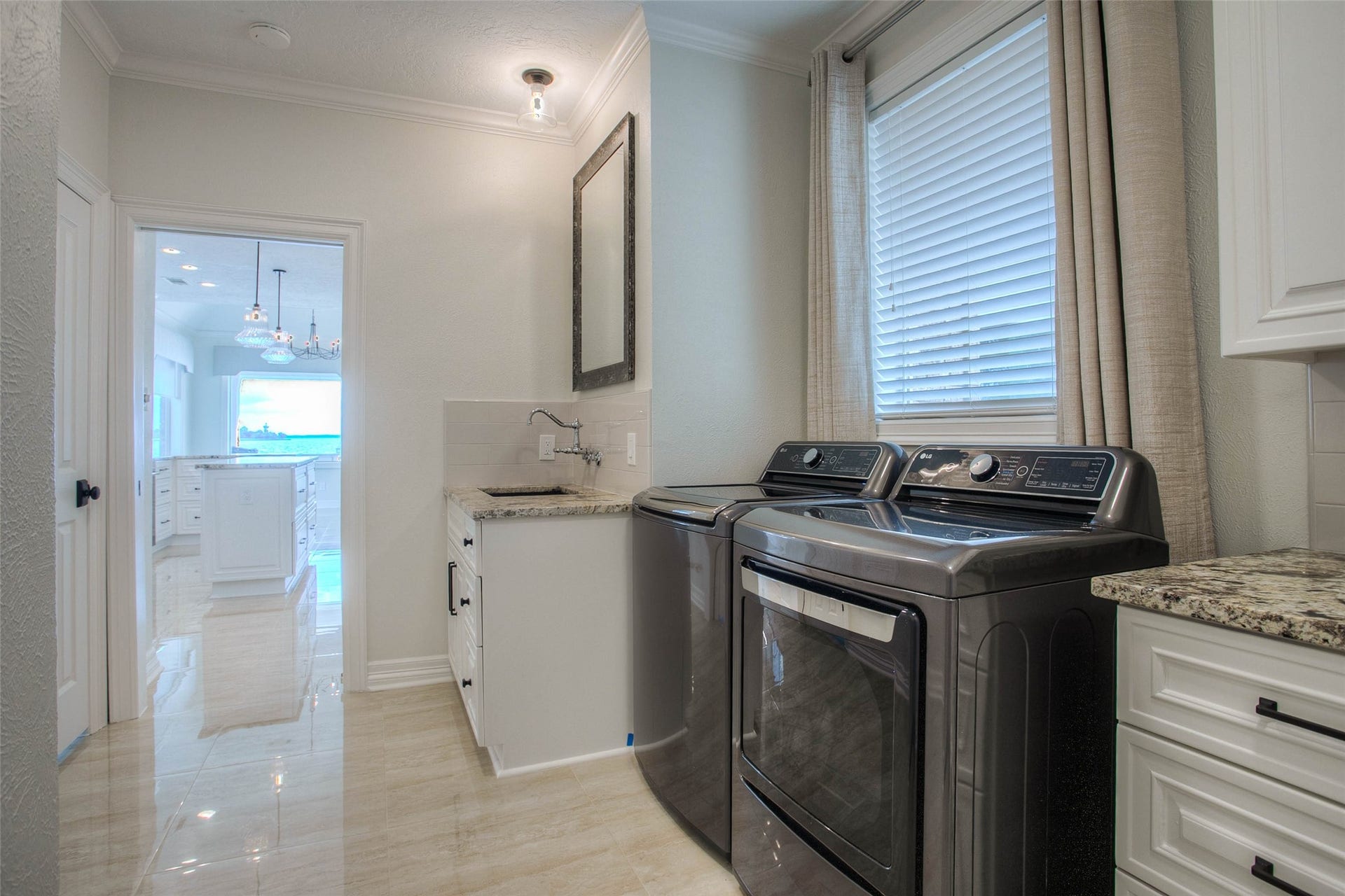 12092 Sagittarius Drive E, Willis, TX 77318 Modern laundry room with sleek appliances, granite countertops, and ample natural light, conveniently situated next to the kitchen.