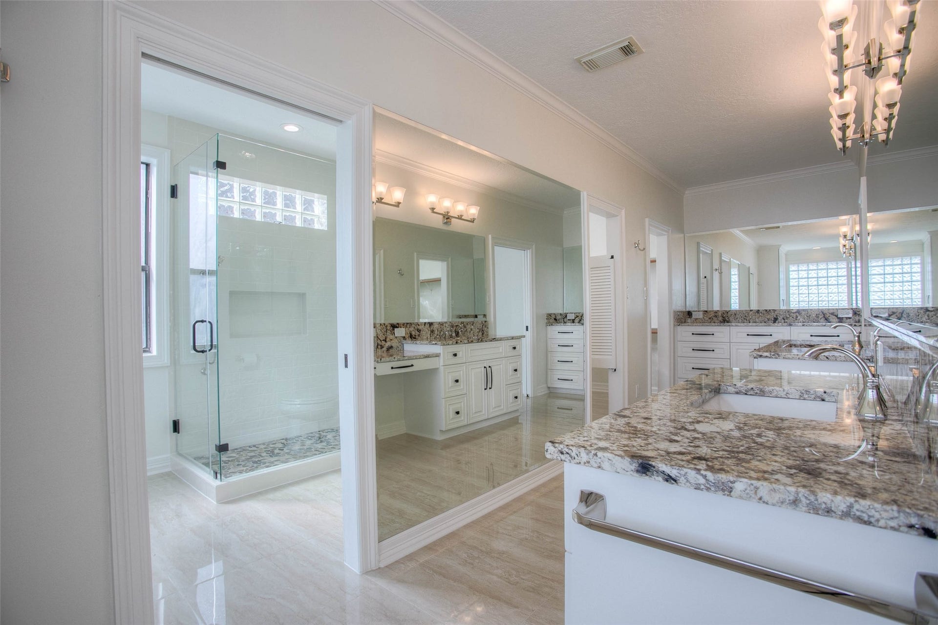 12092 Sagittarius Drive E, Willis, TX 77318 Luxurious bathroom featuring elegant granite countertops, dual sinks, and a spacious glass-enclosed shower, complemented by ample natural light and stylish fixtures.